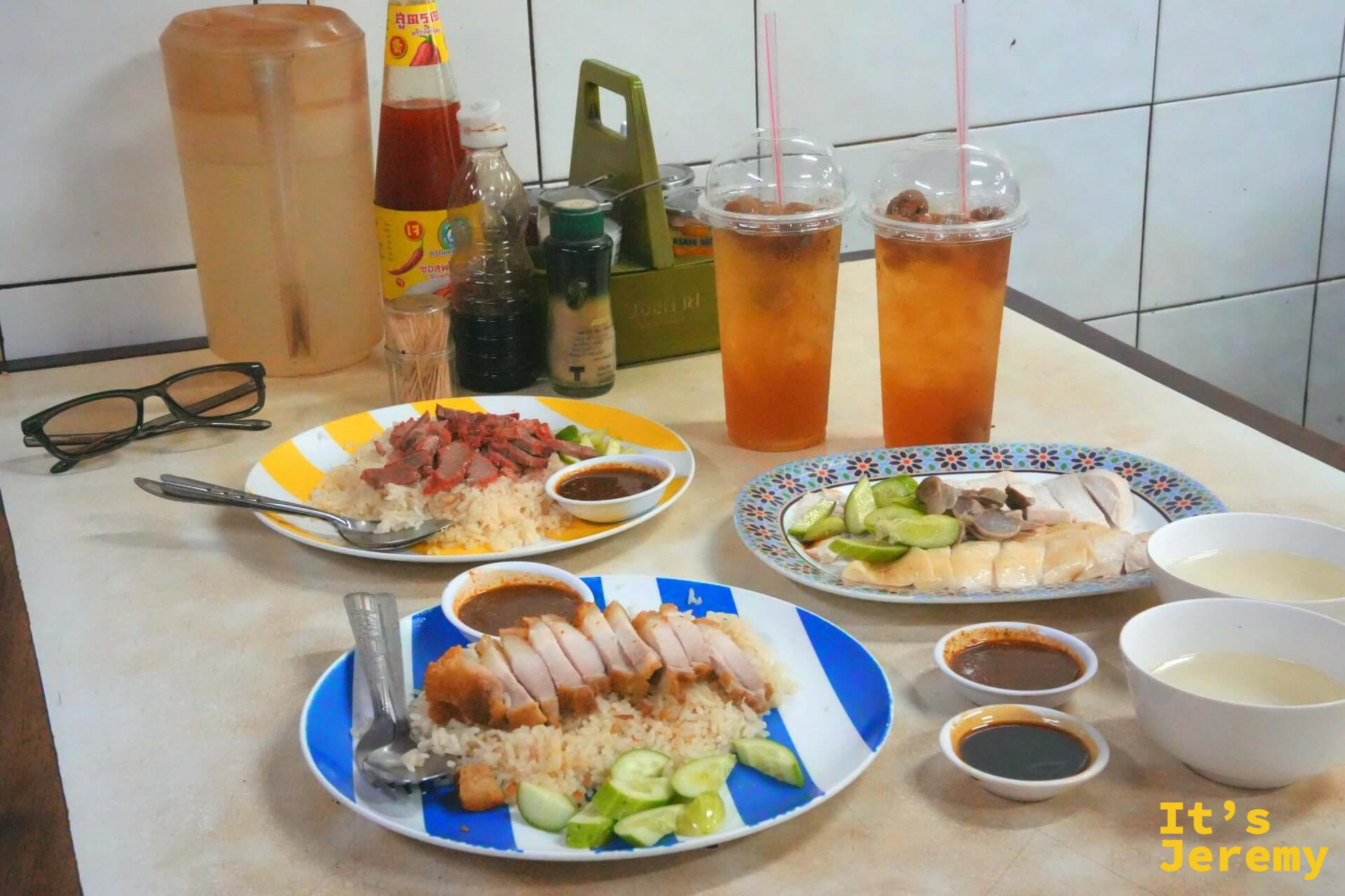 三款配飯同框:脆皮豬、紅燒肉、白斬雞,各附醬汁碗,背景可見調味瓶與兩杯冰飲