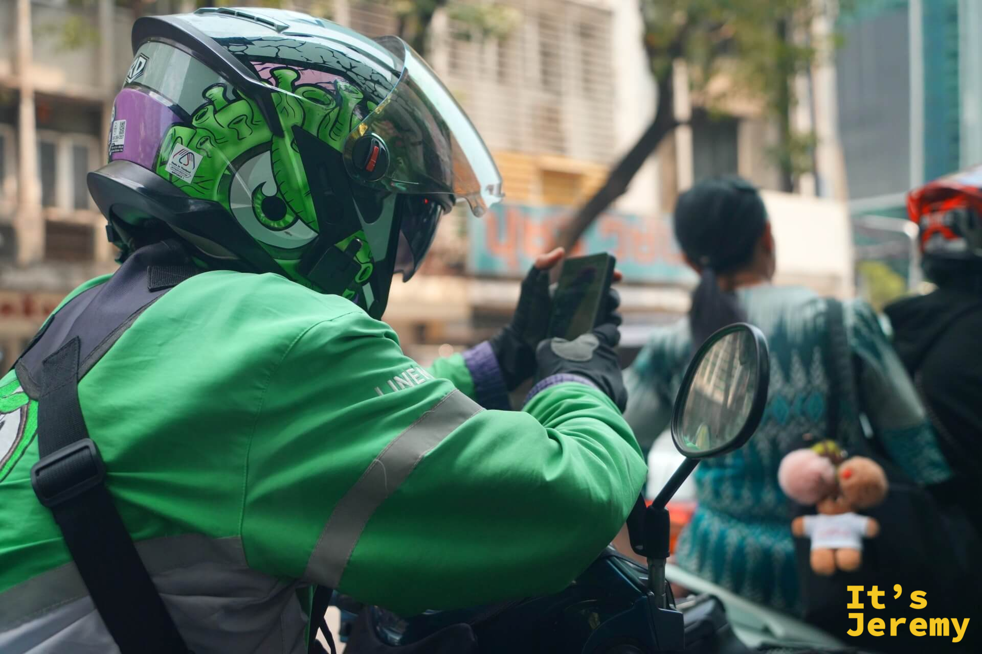 一位 Grab 外送員停紅燈時低頭滑手機,頭盔上的怪獸圖案讓人印象深刻,紅燈滑手機這件事看來不分國籍