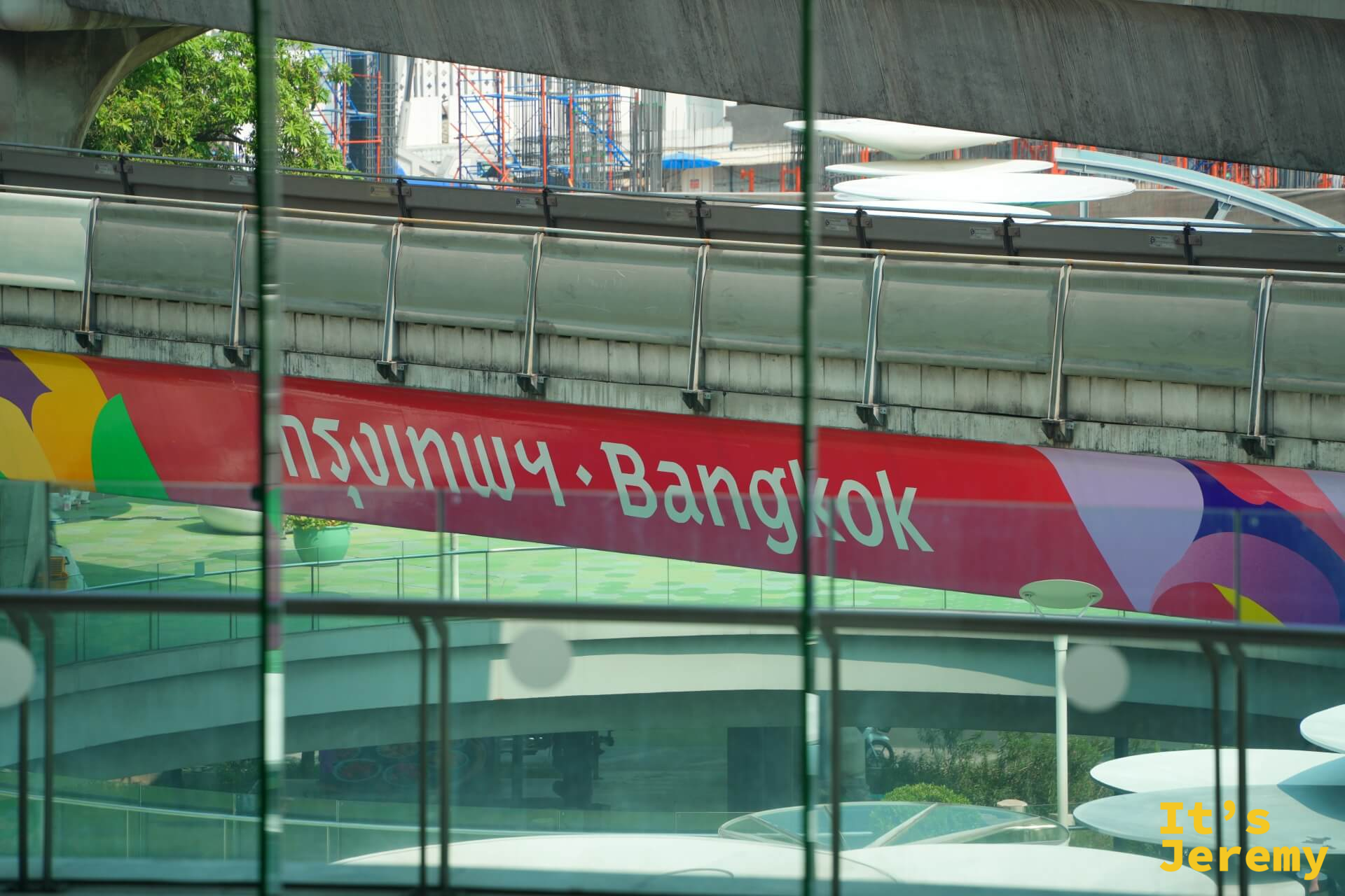透過 BACC 玻璃帷幕看出去，「กรุงเทพ・Bangkok」的 BTS 捷運站牌清晰可見