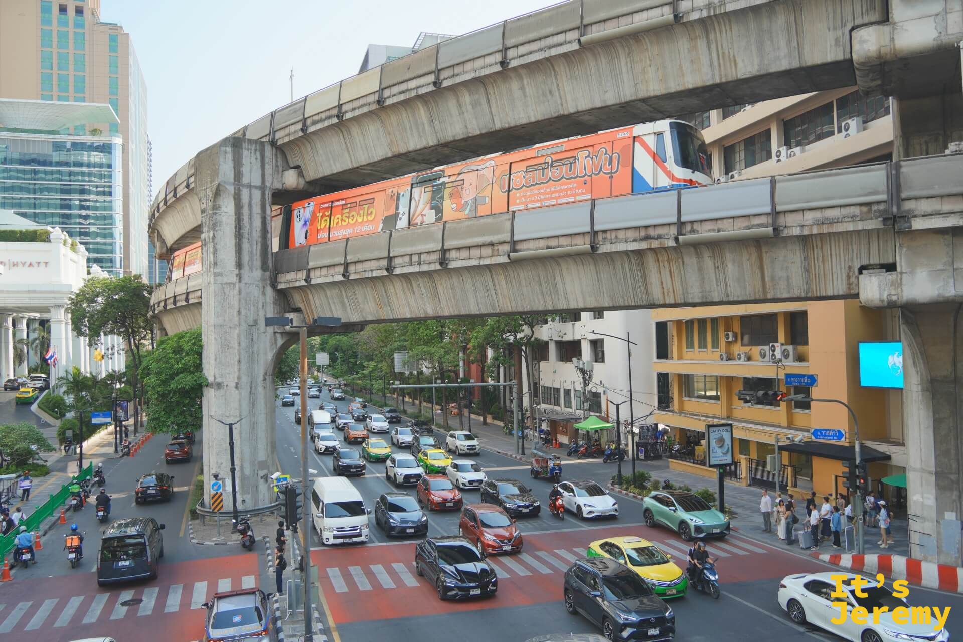 從更高的視角俯拍 BTS Siam 站一帶,電聯車正在進站,下方路口同時塞著幾十輛車,城市密度在這個角度裡壓縮成一張平面