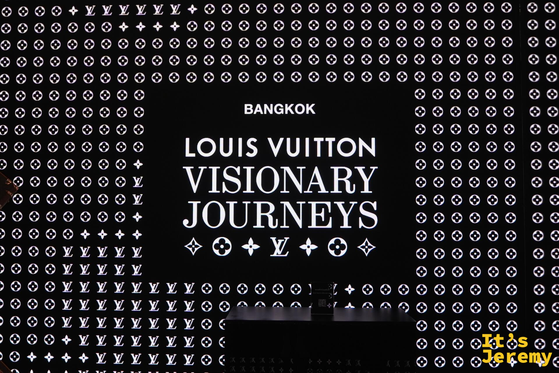 展覽入口黑底白字招牌，LV monogram 滿版背景，BANGKOK LOUIS VUITTON VISIONARY JOURNEYS