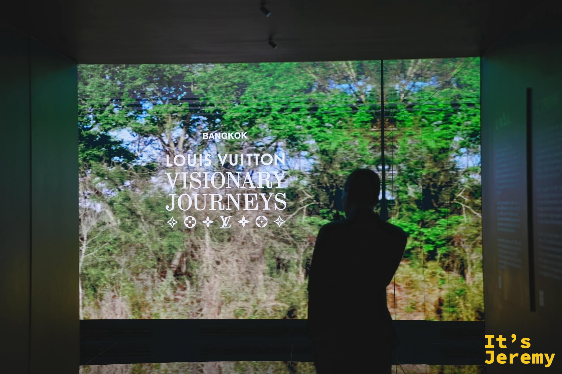 大型投影牆播放品牌形象影像，人物剪影在 LOUIS VUITTON VISIONARY JOURNEYS 字幕前駐足