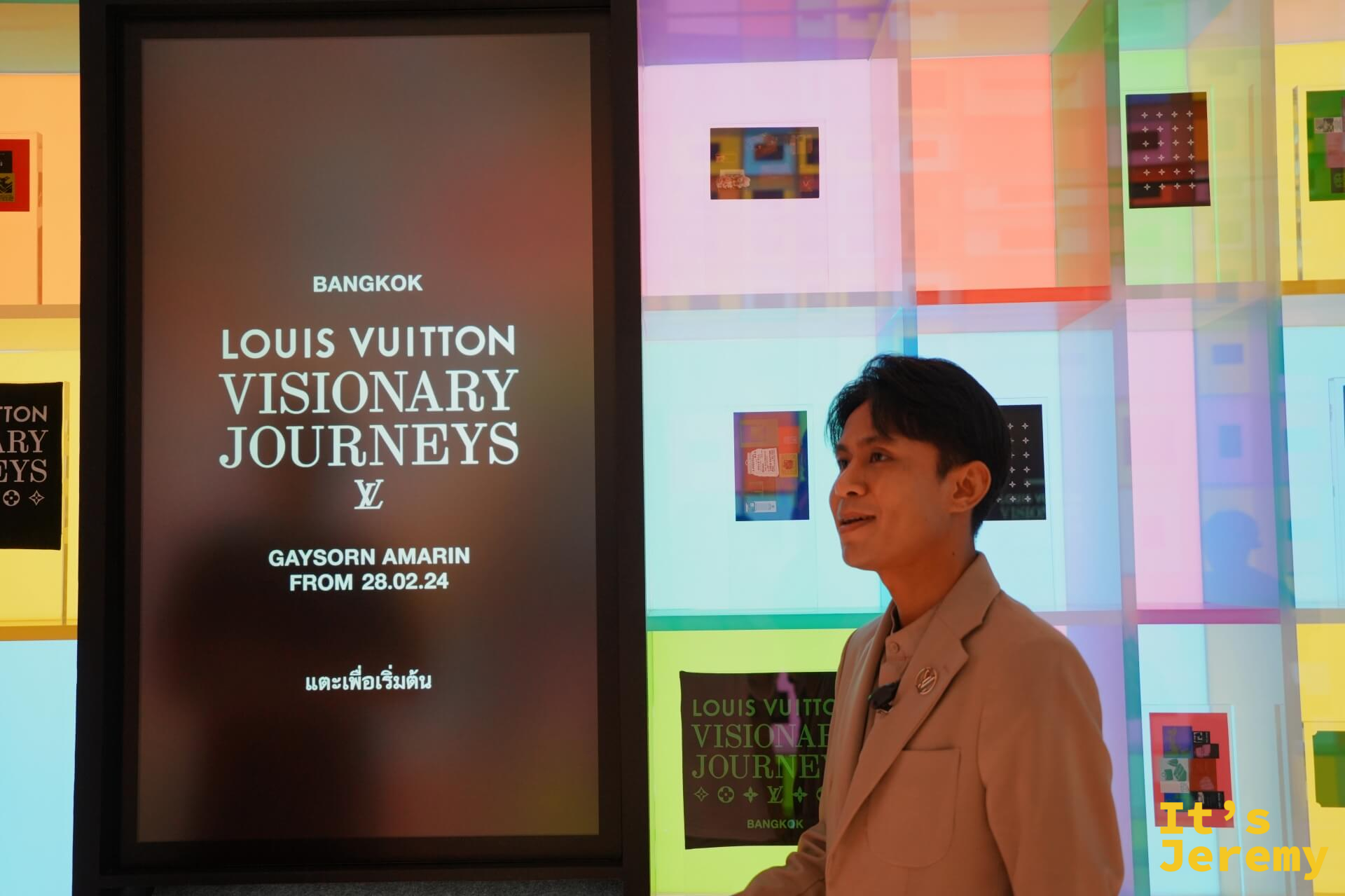 Souvenirs 展間扭蛋機螢幕，顯示 BANGKOK LOUIS VUITTON VISIONARY JOURNEYS 主視覺，背後是繽紛色彩拼貼牆