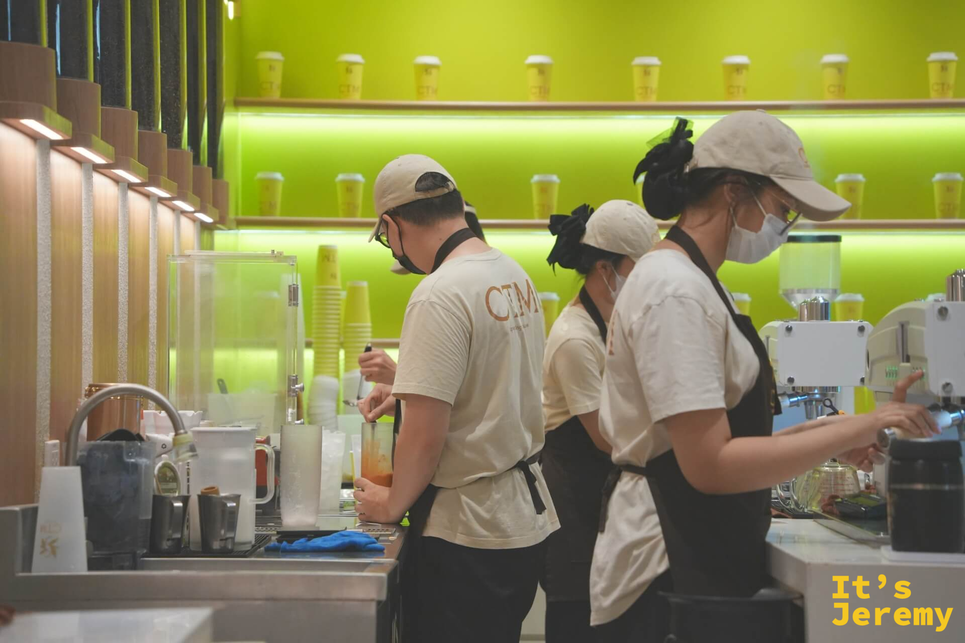 四位 CTM 店員在電黃色吧台後各守一道工序