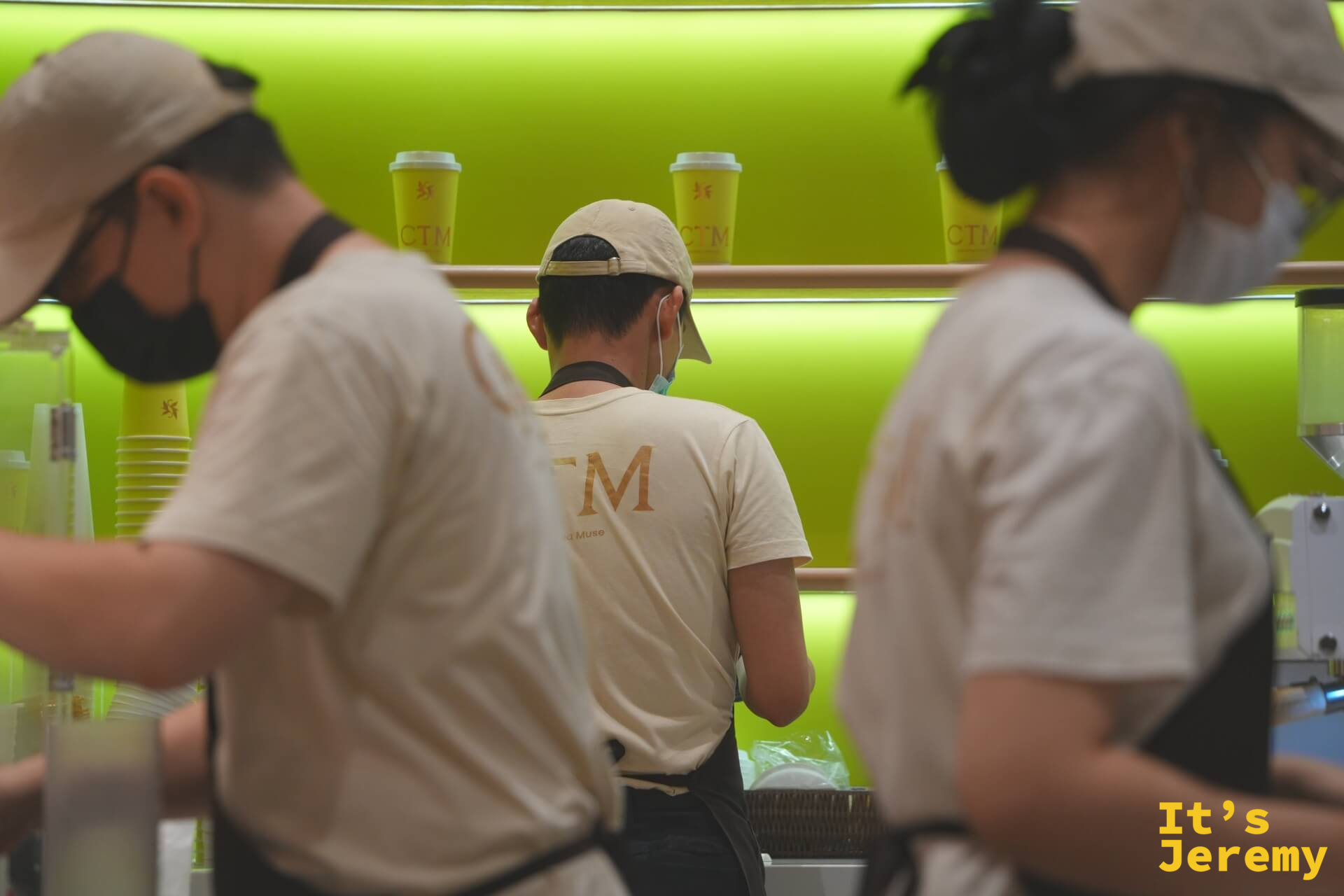 三位店員從背後看去,電黃色牆面排滿 CTM 外帶杯