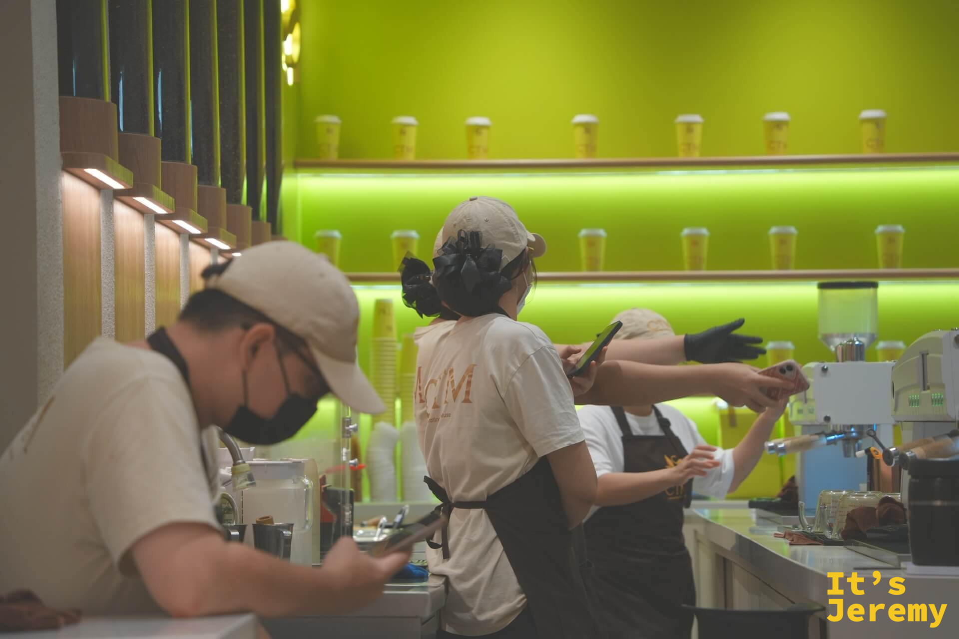 前方男性店員低頭滑手機,後方兩位店員似乎在聊天