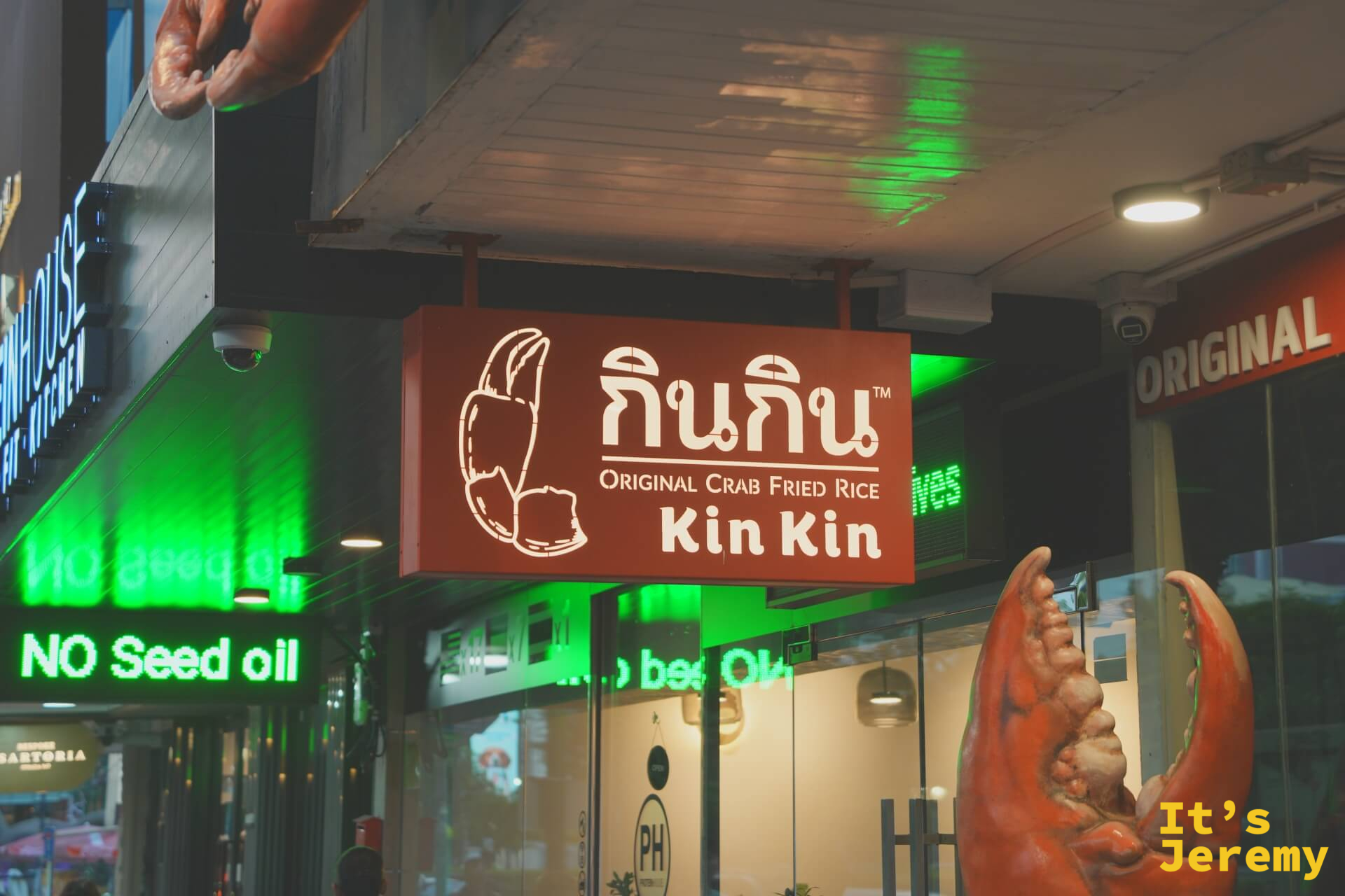入夜的招牌燈箱近照：「กินกิน Original Crab Fried Rice Kin Kin」，紅配綠霓虹，是蘇坤蔚路上標準的曼谷夜晚配色