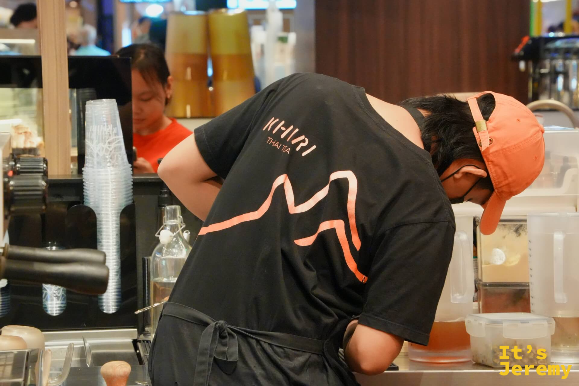 備料中的員工，黑色 KHIRI Thai Tea 制服背面印著品牌山型圖案