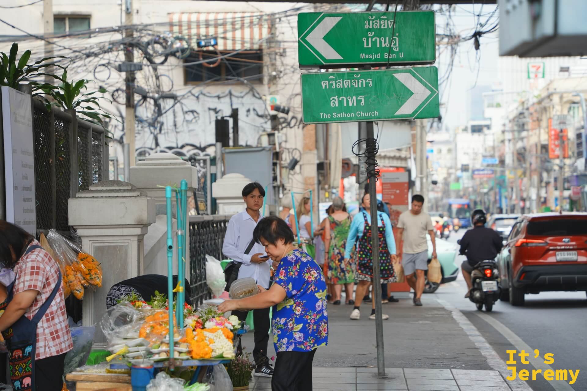石龍軍路路口,綠色英文路標指向 Masjid Ban U 和 The Sathon Church,前景有花攤