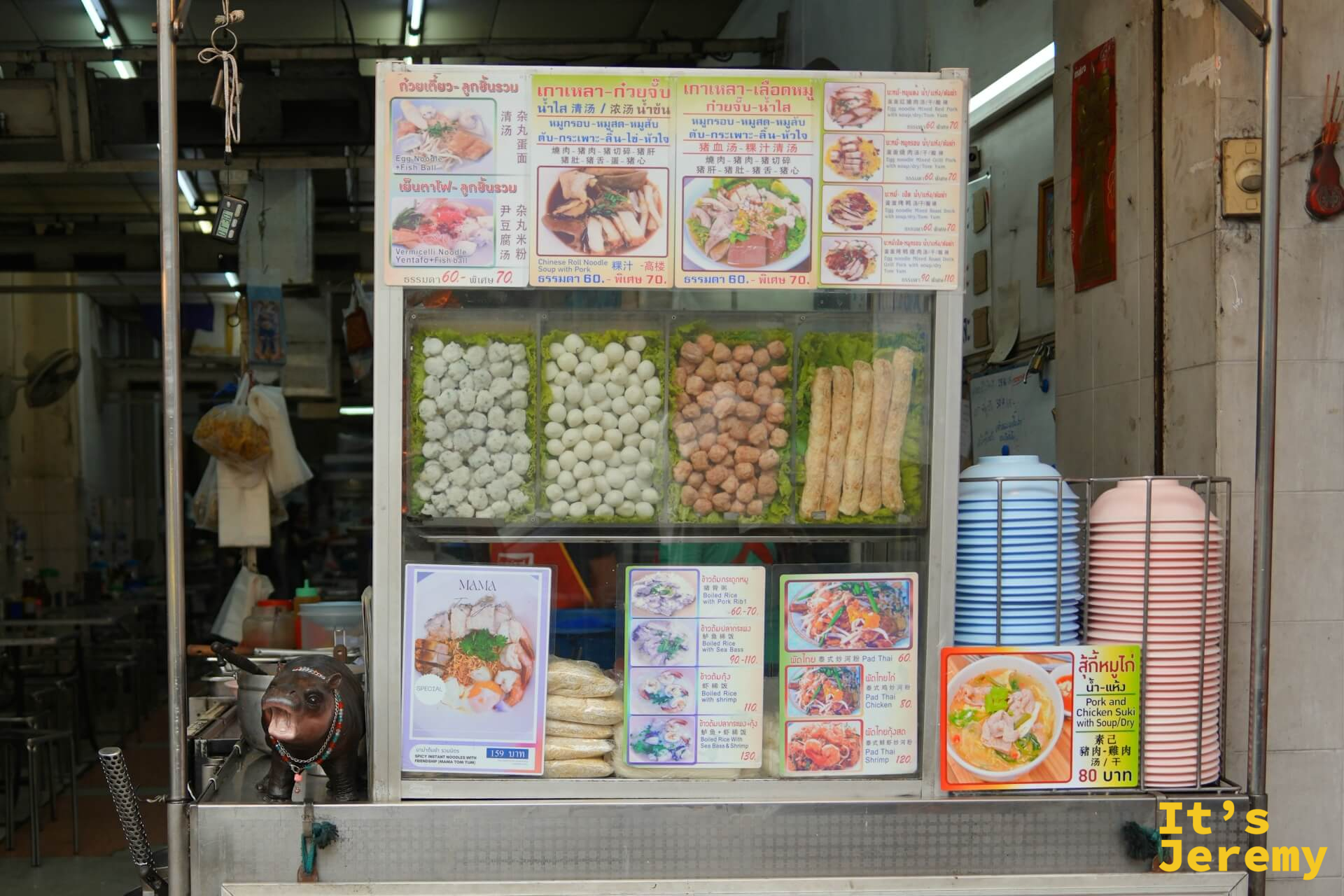 展示台裡排列著白色手工魚丸、炸魚丸,上方有菜單圖卡,右側是疊起的藍色碗盤