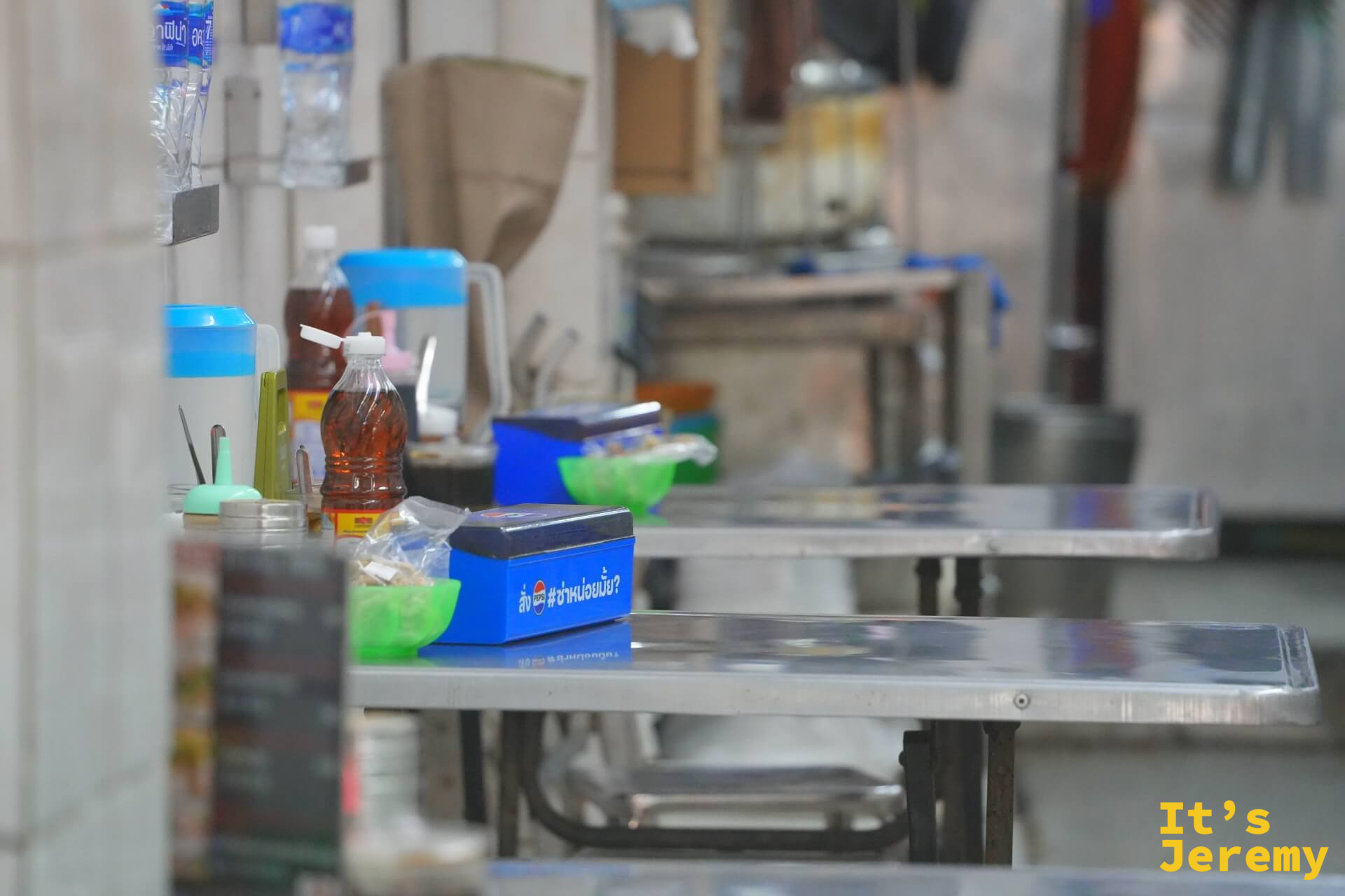 不鏽鋼桌椅排成一列的用餐空間,桌上擺著調味料和Pepsi藍色外送箱