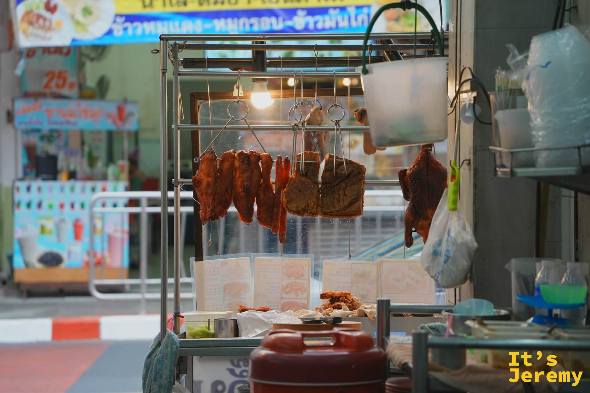 灶龍店門口側面,燈光下掛著整排烤豬肉,背後是石龍軍路的街道景色