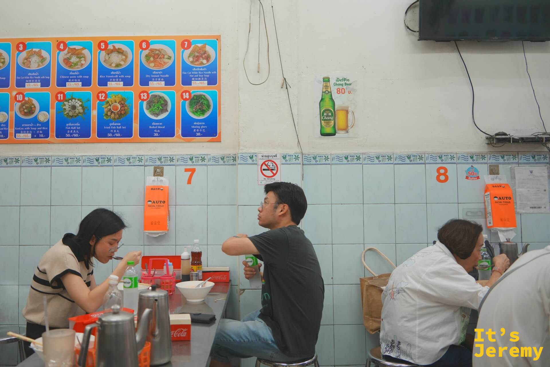 店內用餐場景:桌椅排列整齊,牆上掛著彩色圖片菜單板,客人安靜地在座位上吃麵,桌面標有數字編號