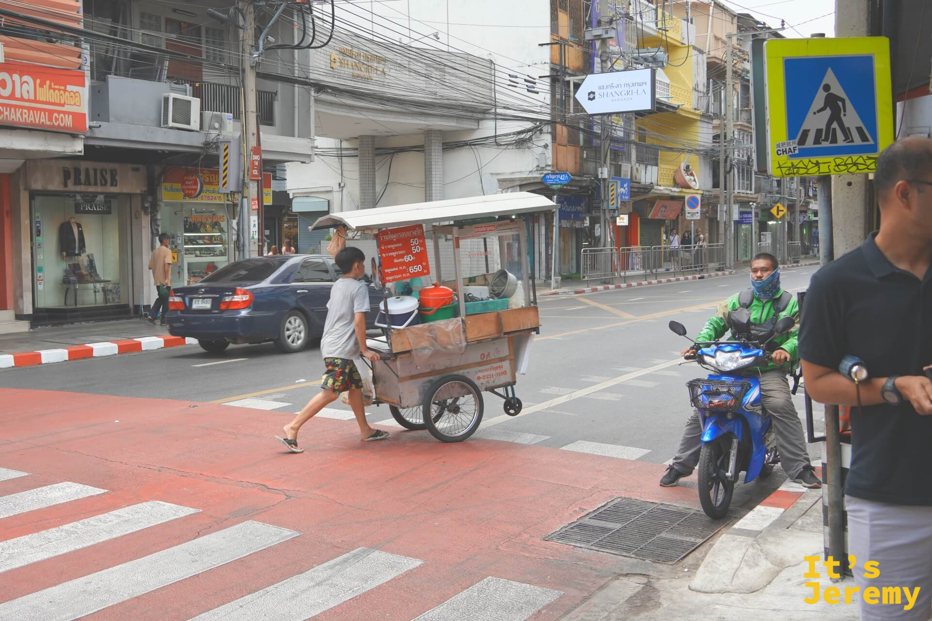 石龍軍路十字路口,少年推著附有菜單招牌的流動餐車穿越斑馬線