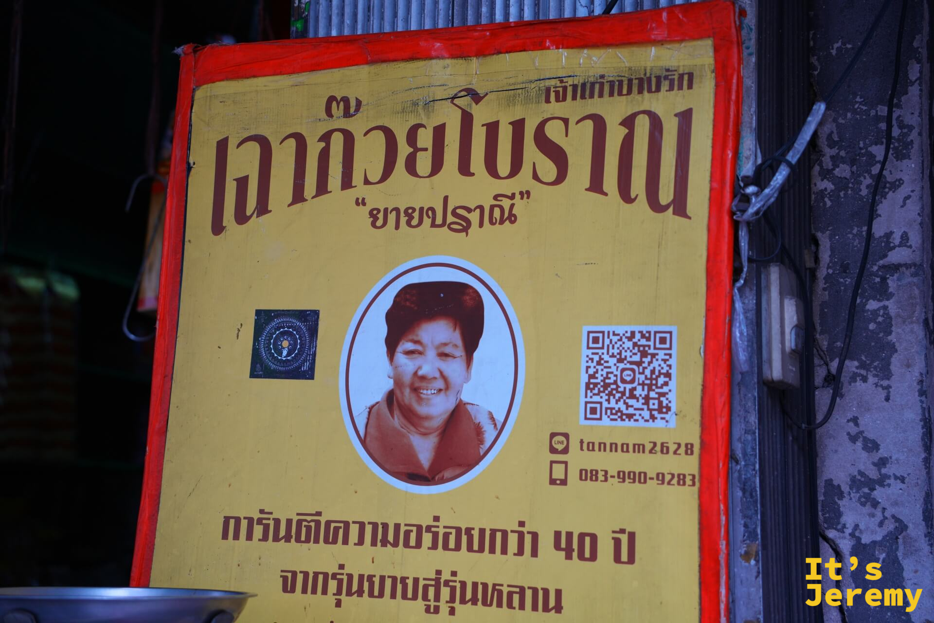 Charoen Krung 路邊攤的黃底紅框招牌,寫著「เฉาก๊วยโบราณ ยายปราณี」與保證40年美味的文字,附有創始人阿嬤的肖像照
