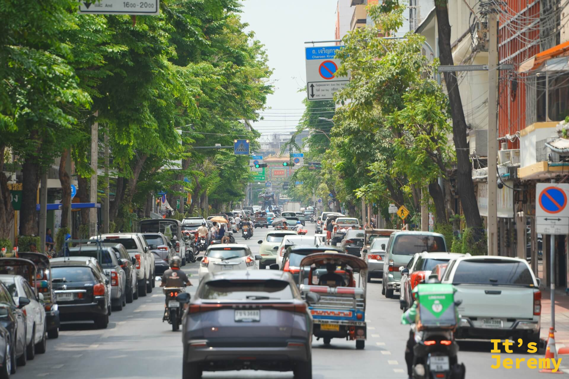 石龍軍路主幹道的白天車流,兩側行道樹,嘟嘟車在其中