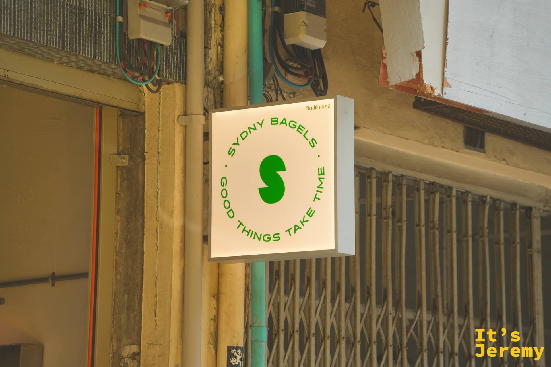 SYDNY BAGELS 招牌燈箱，白底綠字，店訓「Good Things Take Time」清晰可見