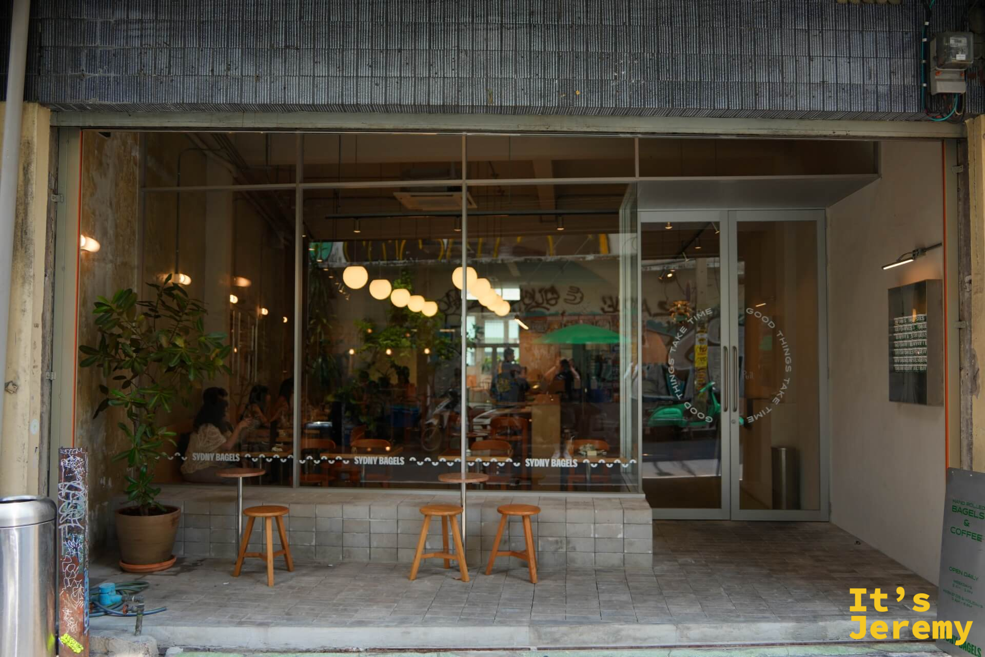 透過落地玻璃窗可以看到裡面坐著用餐的客人，外設木製凳子