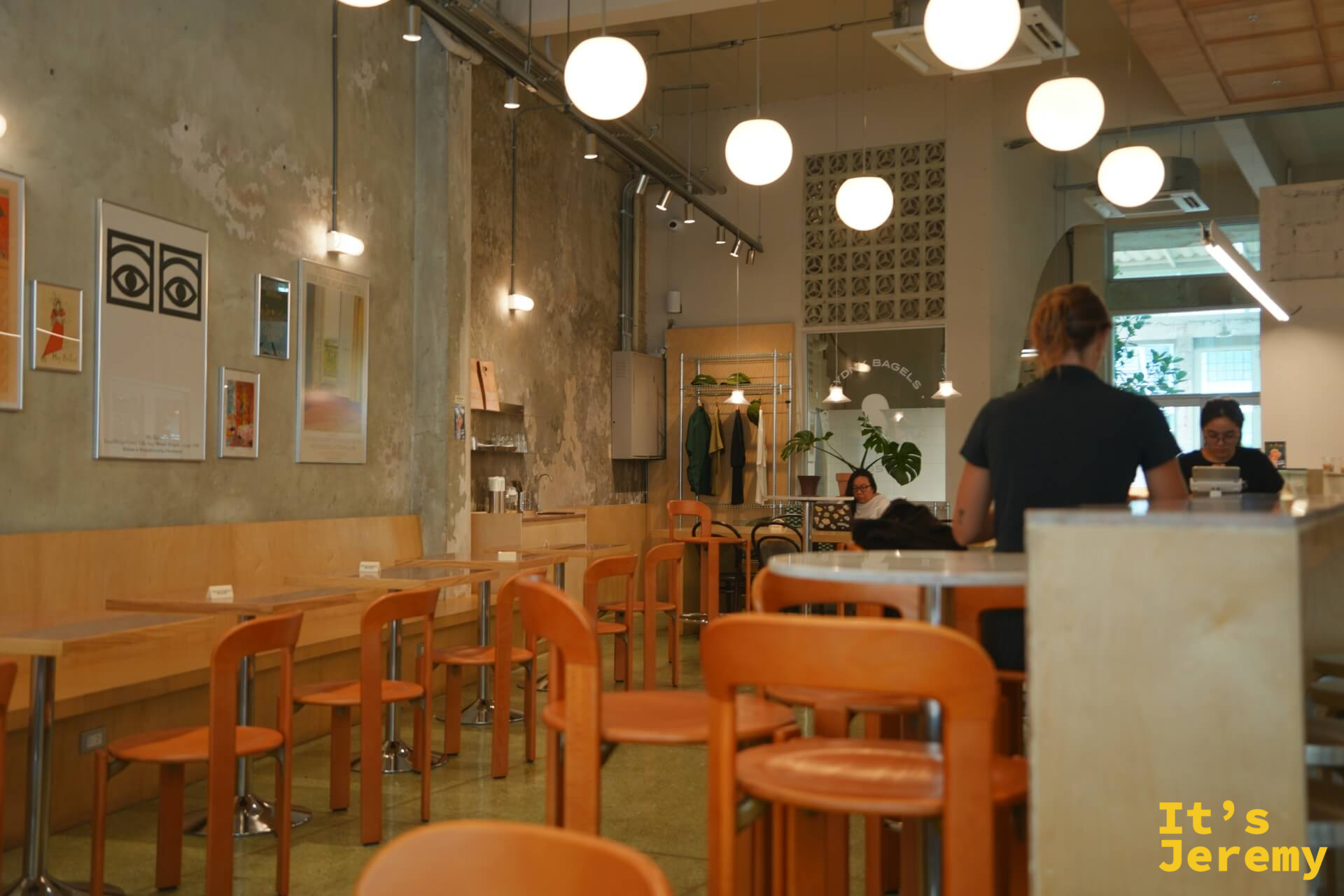 店內空間：橘色椅、球形吊燈、水泥質感牆面，牆上掛著藝術畫作，整體氛圍沉靜