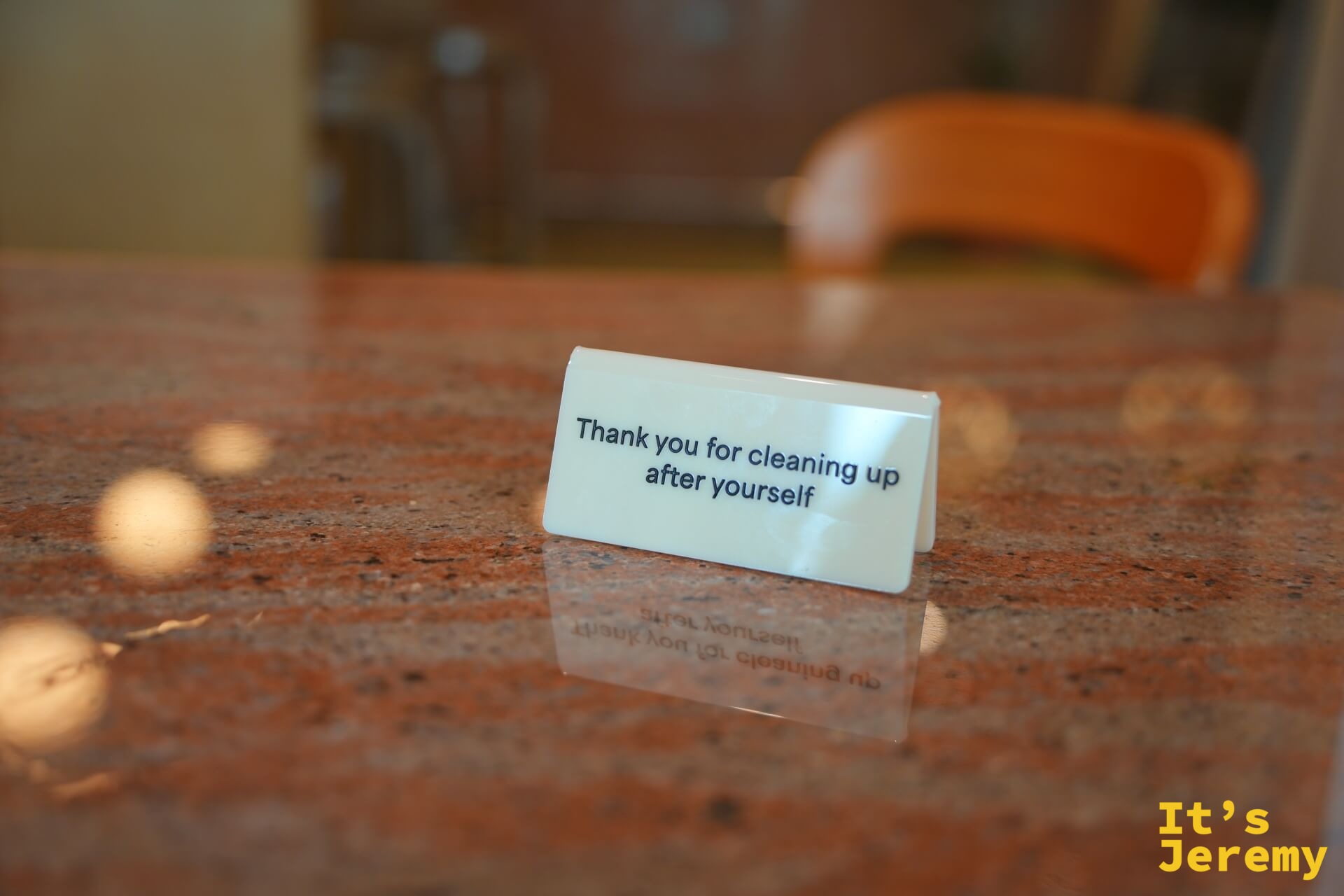 桌面上的透明小立牌：「Thank you for cleaning up after yourself」，映照在大理石紋桌面上