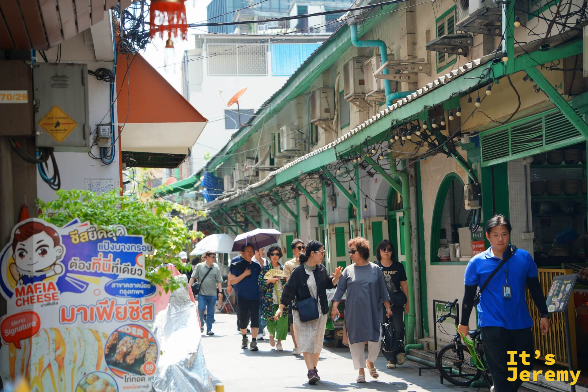 綠色殖民拱廊店屋排開,幾名遊客在廊下走動