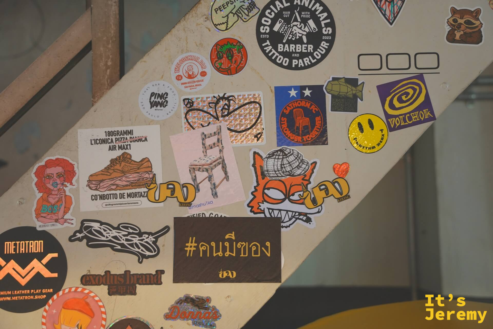 樓梯欄杆面密布貼紙:「Social Animals Barber & Tattoo Parlour」、「#คนมีของ」、各式插圖