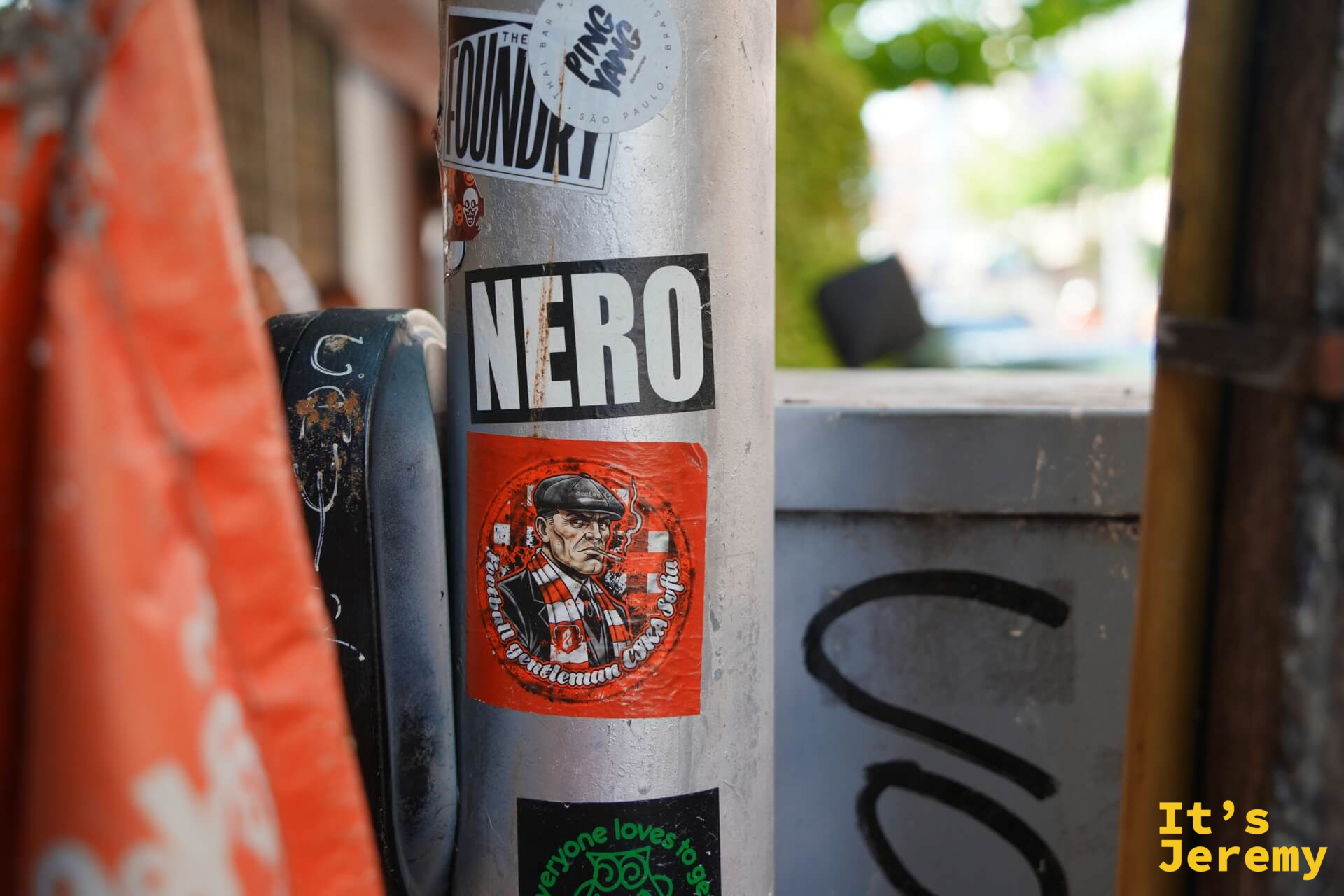 路燈柱上的「NERO」黑白貼紙和紳士插圖,旁邊垂著橘紅色旗幟