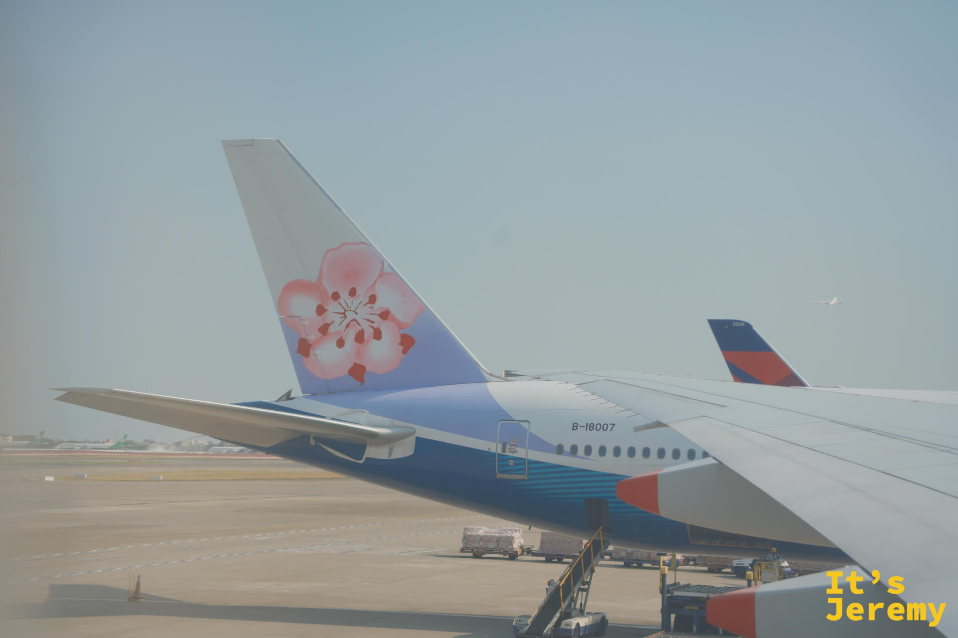 桃園機場停機坪，窗外可見華航梅花尾翼，機身號碼 B-18007，另一側停著達美航班