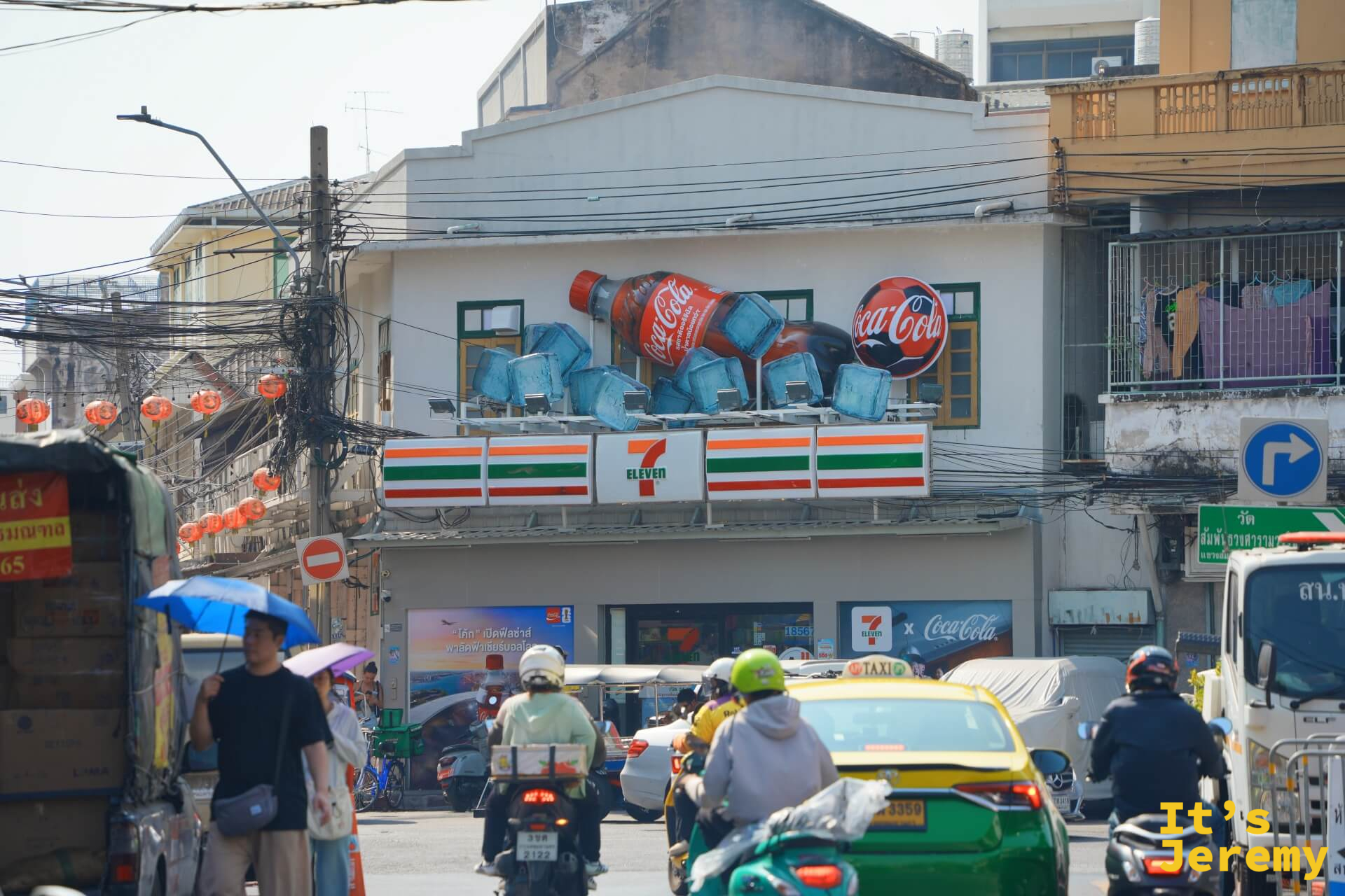 街口 7-Eleven 外牆上方有立體 Coca-Cola 玻璃瓶廣告裝置,前景是交通與行人