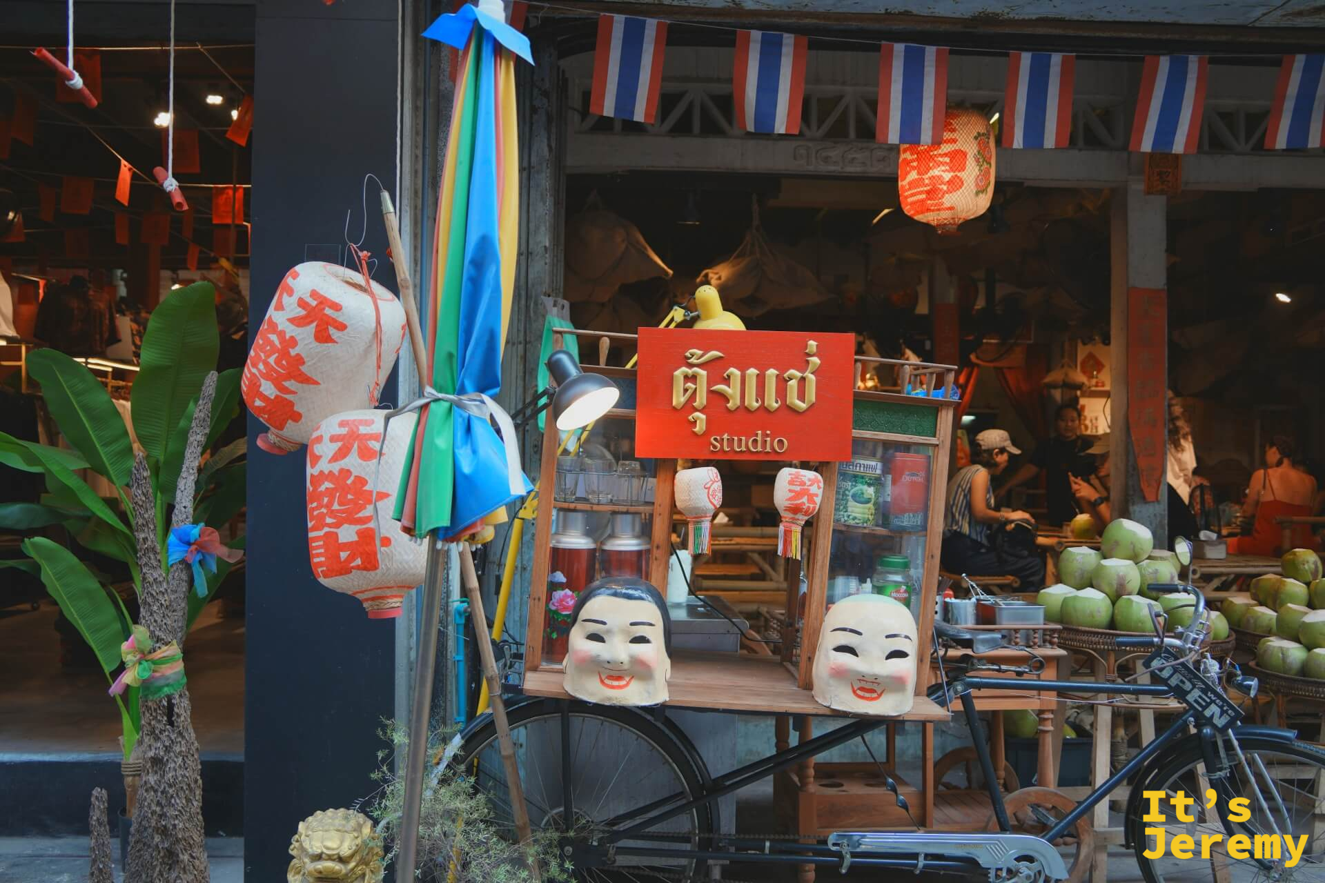 「ตั้งแช่ studio」店前:老腳踏車、中文紅燈籠、舞獅臉具與彩色小旗,民俗感強烈的街頭布置