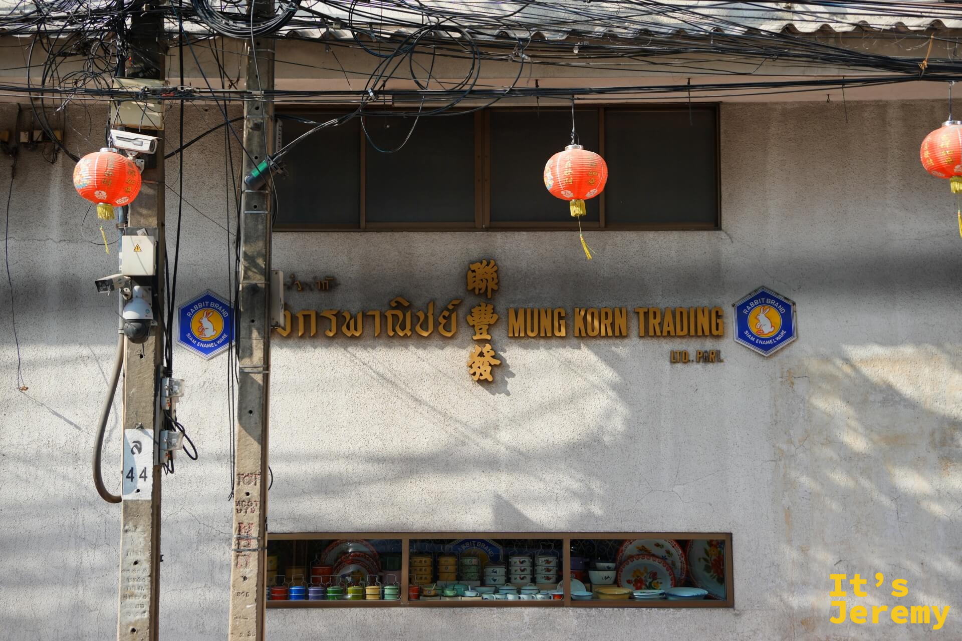「聯豐 Mung Korn Trading 益商號」百年老建築立面,窗台陳列彩色搪瓷碗盤,兩側掛著橘紅燈籠