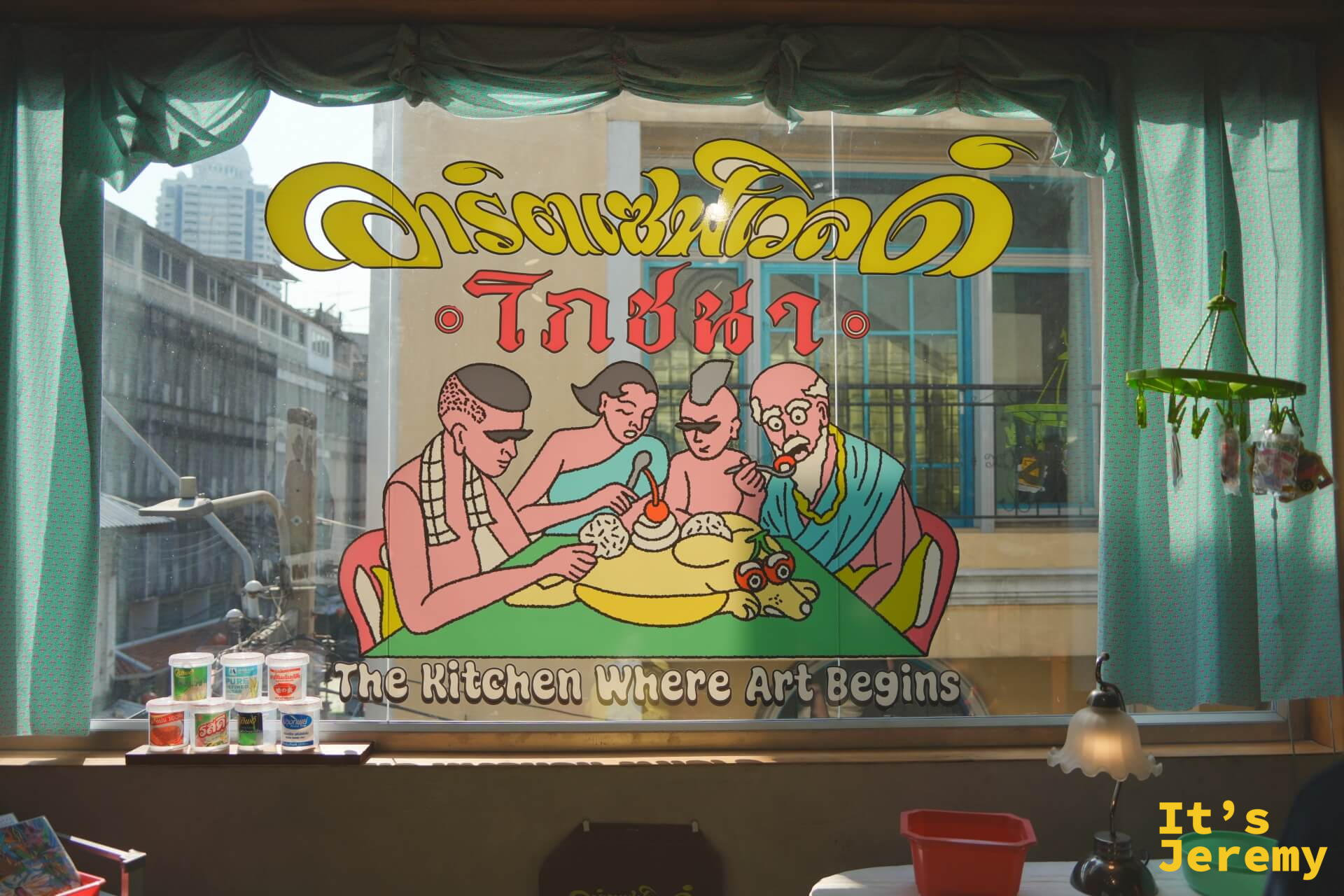 「The Kitchen Where Art Begins」玻璃窗藝術壁畫:幾個光頭人物圍桌而食,復古插畫風格,自外可見