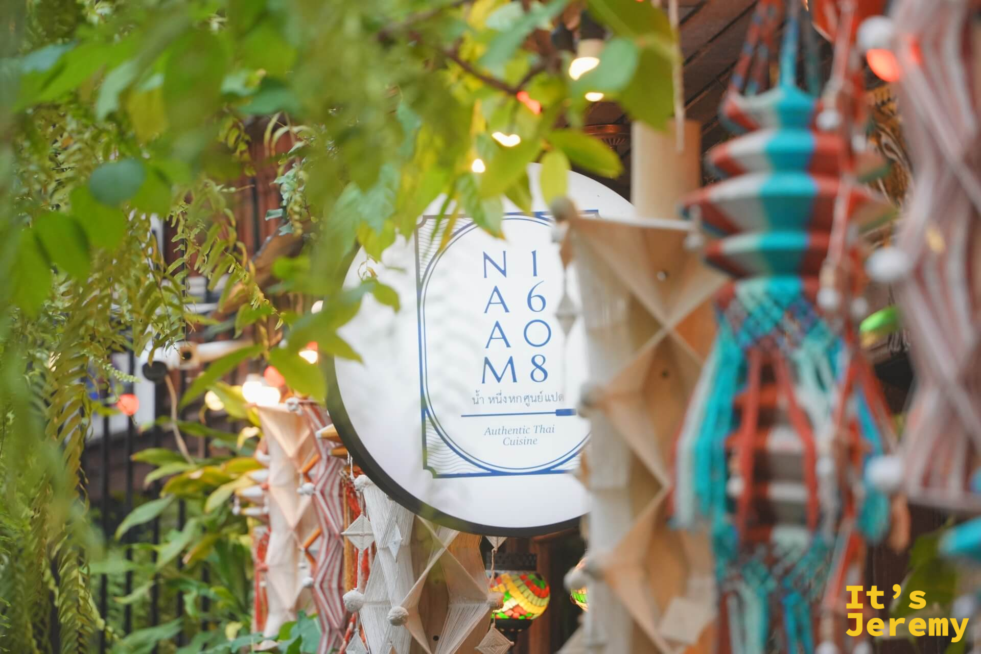 NAAM 1608 招牌被蕨類與手工編織飾品環繞，暖光打在招牌圓盤上