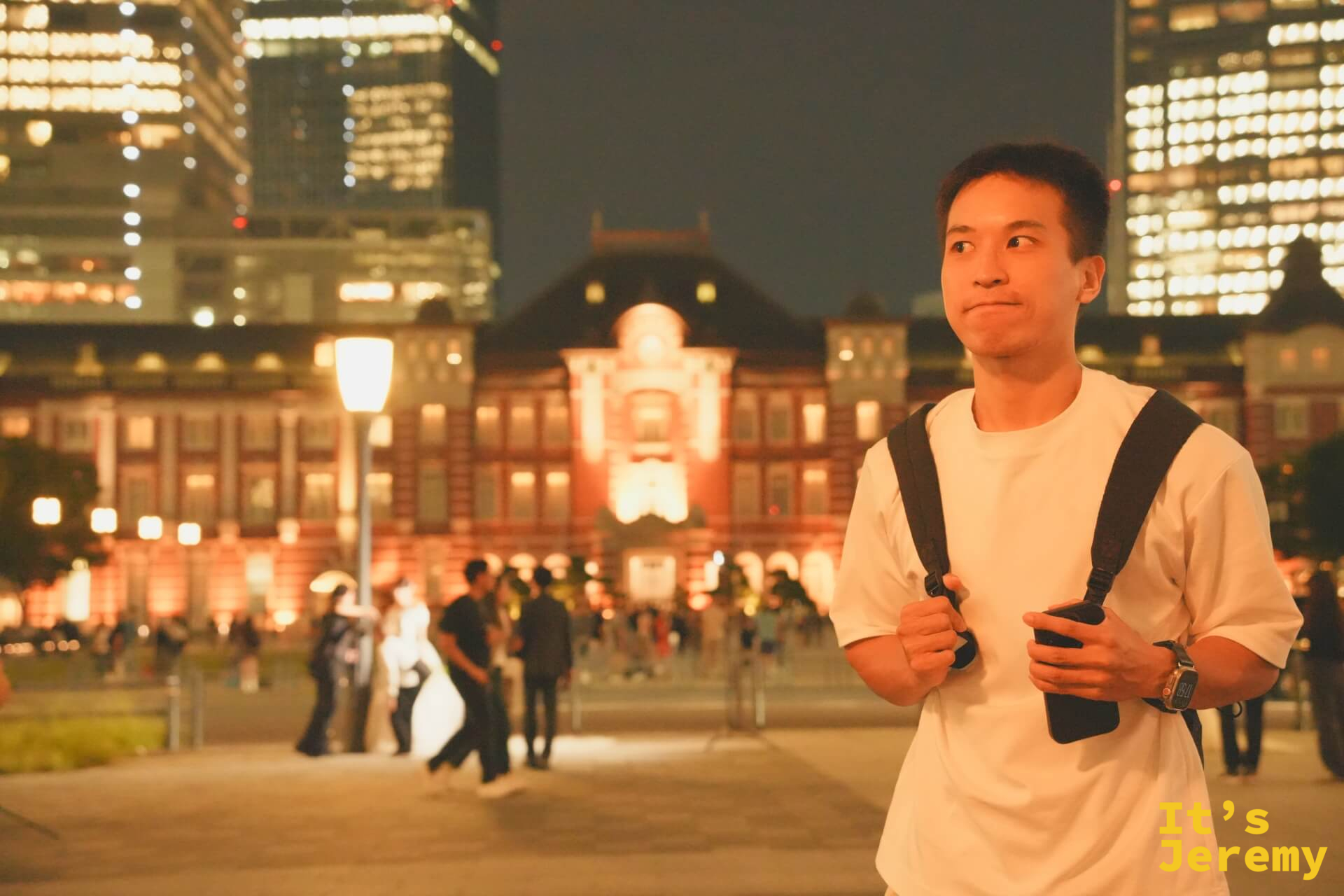 Jeremy 站在廣場,橘紅燈光下的東京車站在身後清晰展開