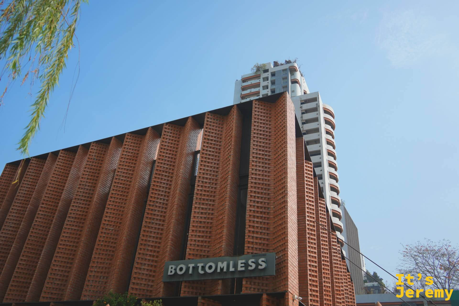 BOTTOMLESS Coffee Roasters 蘇坤蔚 33 號本店外觀仰角全景,紅磚外牆與藍天