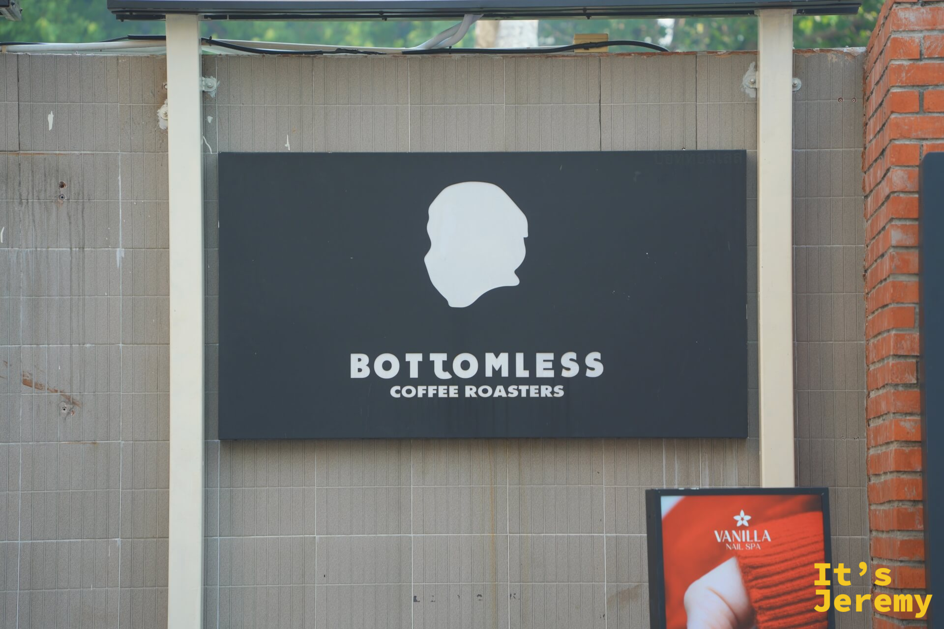BOTTOMLESS Coffee Roasters 黑底白字 logo 招牌，人頭側面剪影設計