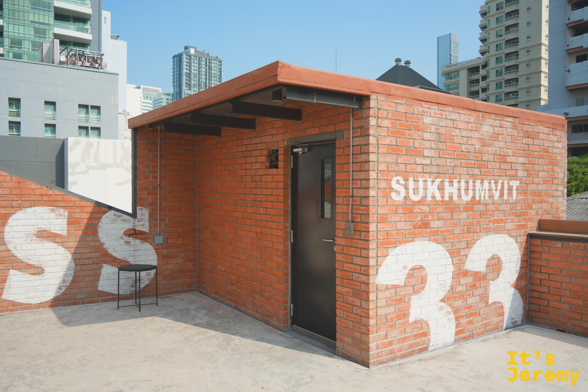 三樓天台出口磚房，上面寫有「SUKHUMVIT 33」字樣，旁邊有一把椅子