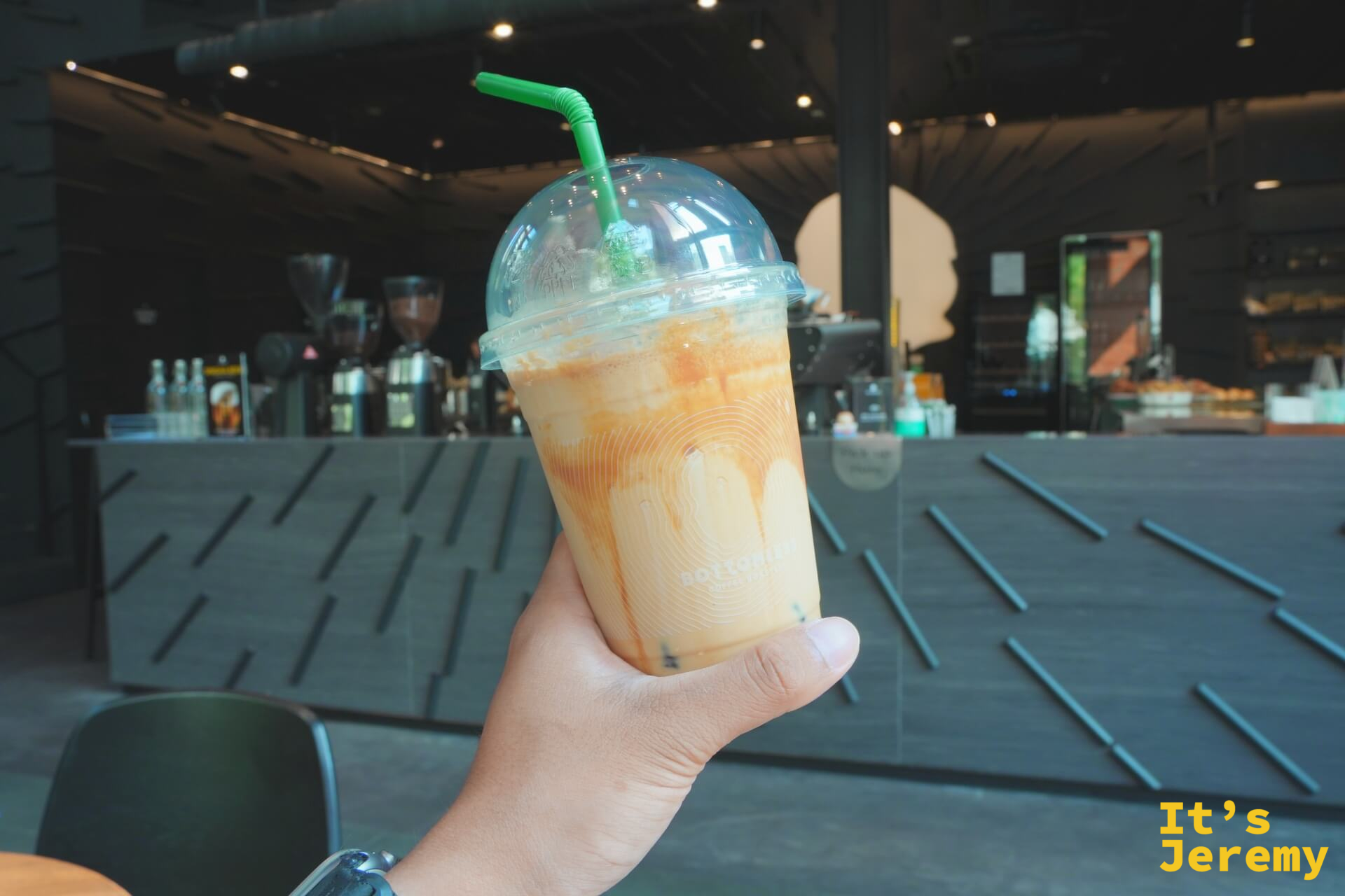 手持 BOTTOMLESS Iced Salted Caramel Macchiato，背景為一樓吧台