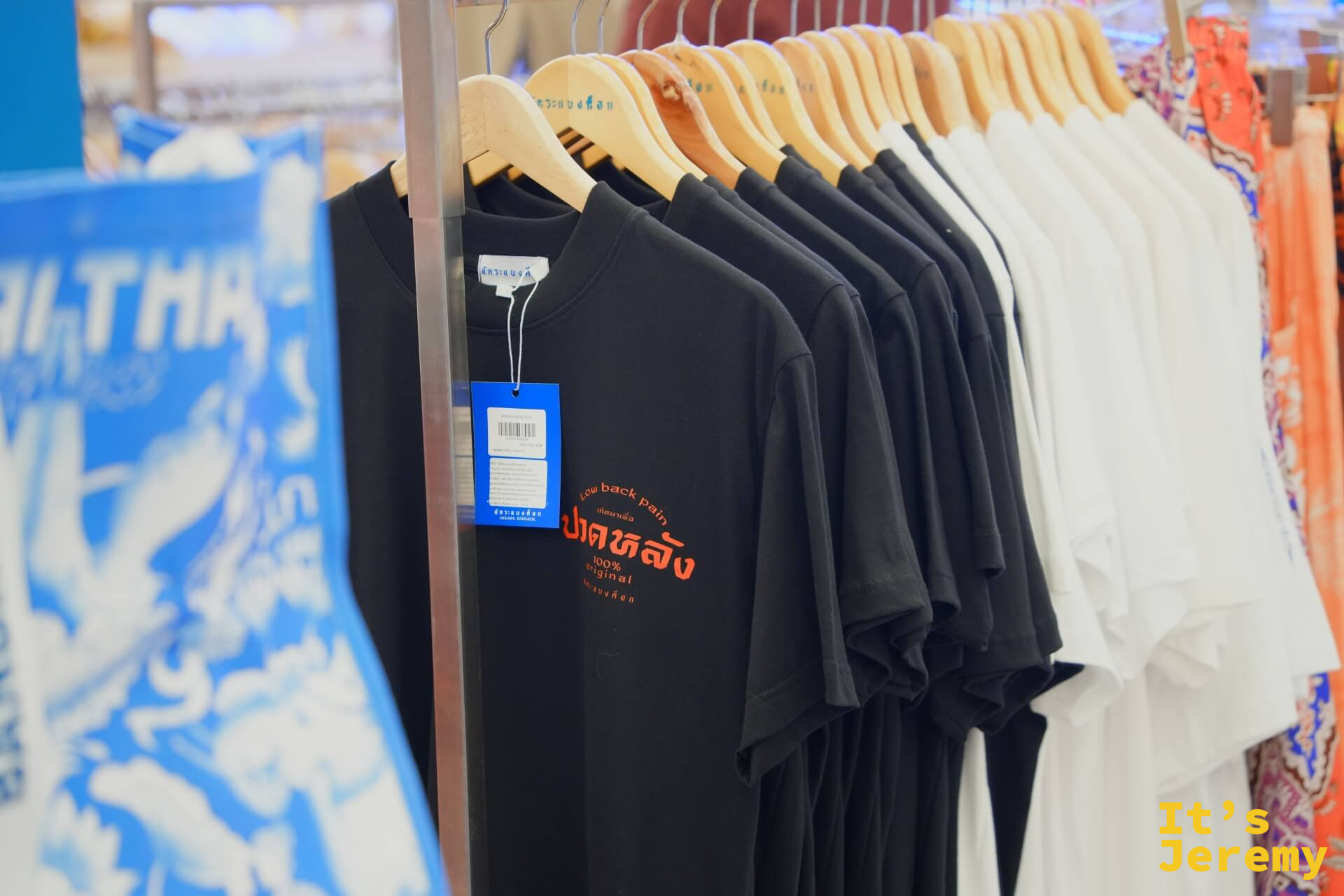 Thai Thai Market 幽默泰文 T 恤展示架,黑色上衣印「ปาดหลัง(腰痛)」橘色泰文字樣