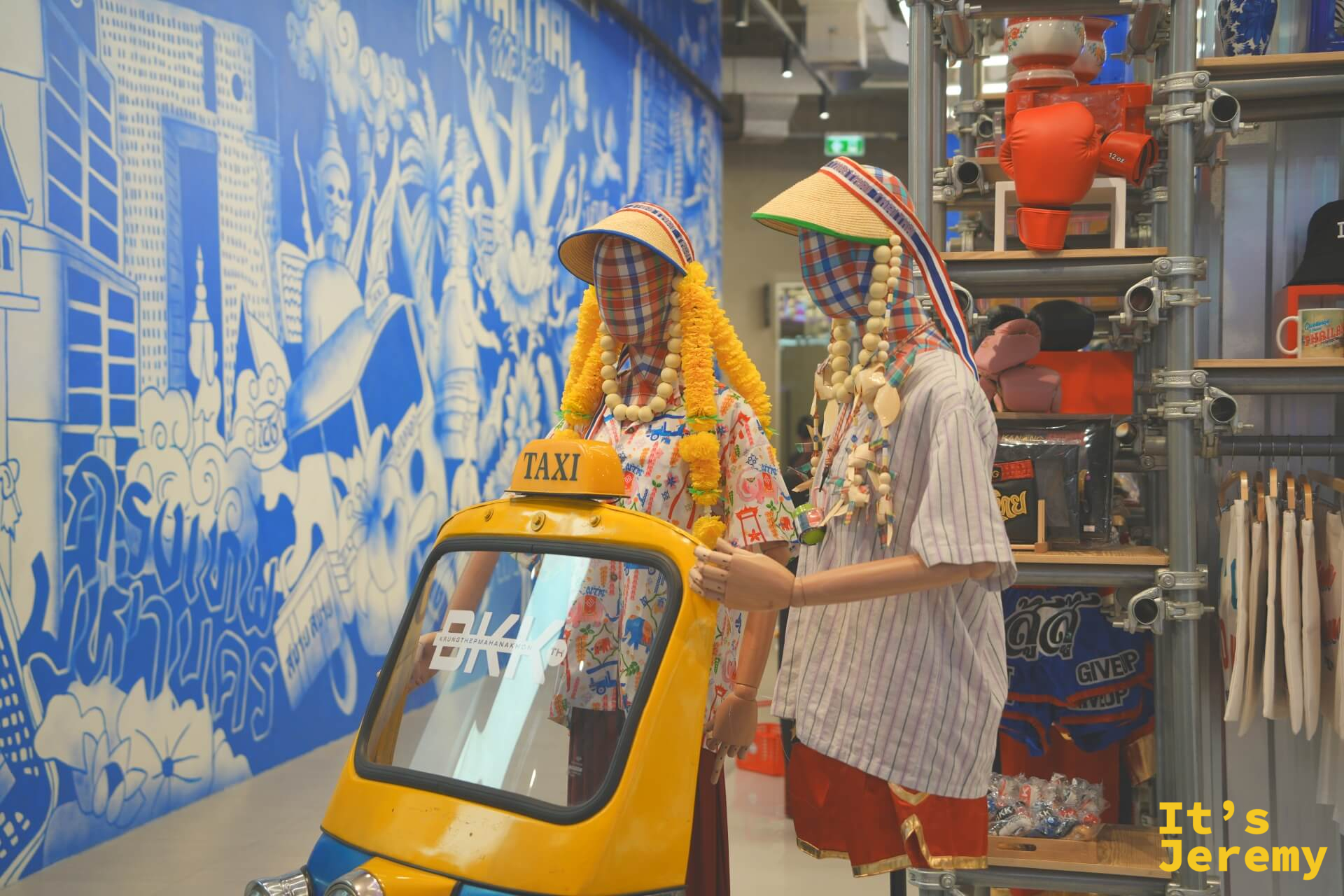 Thai Thai Market,嘟嘟車與身著泰式服裝假人並陳,背景是藍白色泰式城市插畫壁畫