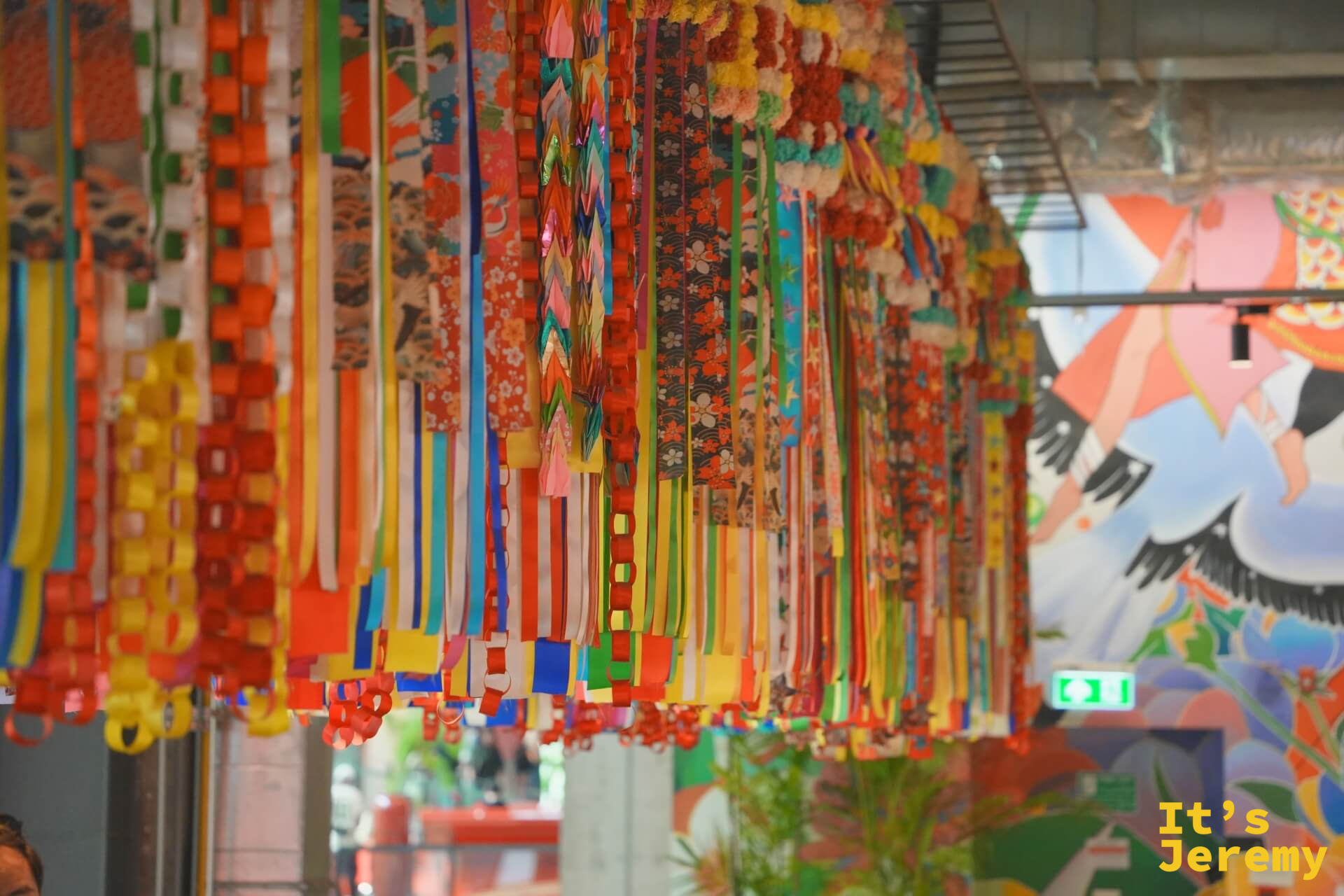 彩色流蘇緞帶裝飾垂掛走廊,背景可見鮮豔花鳥壁畫