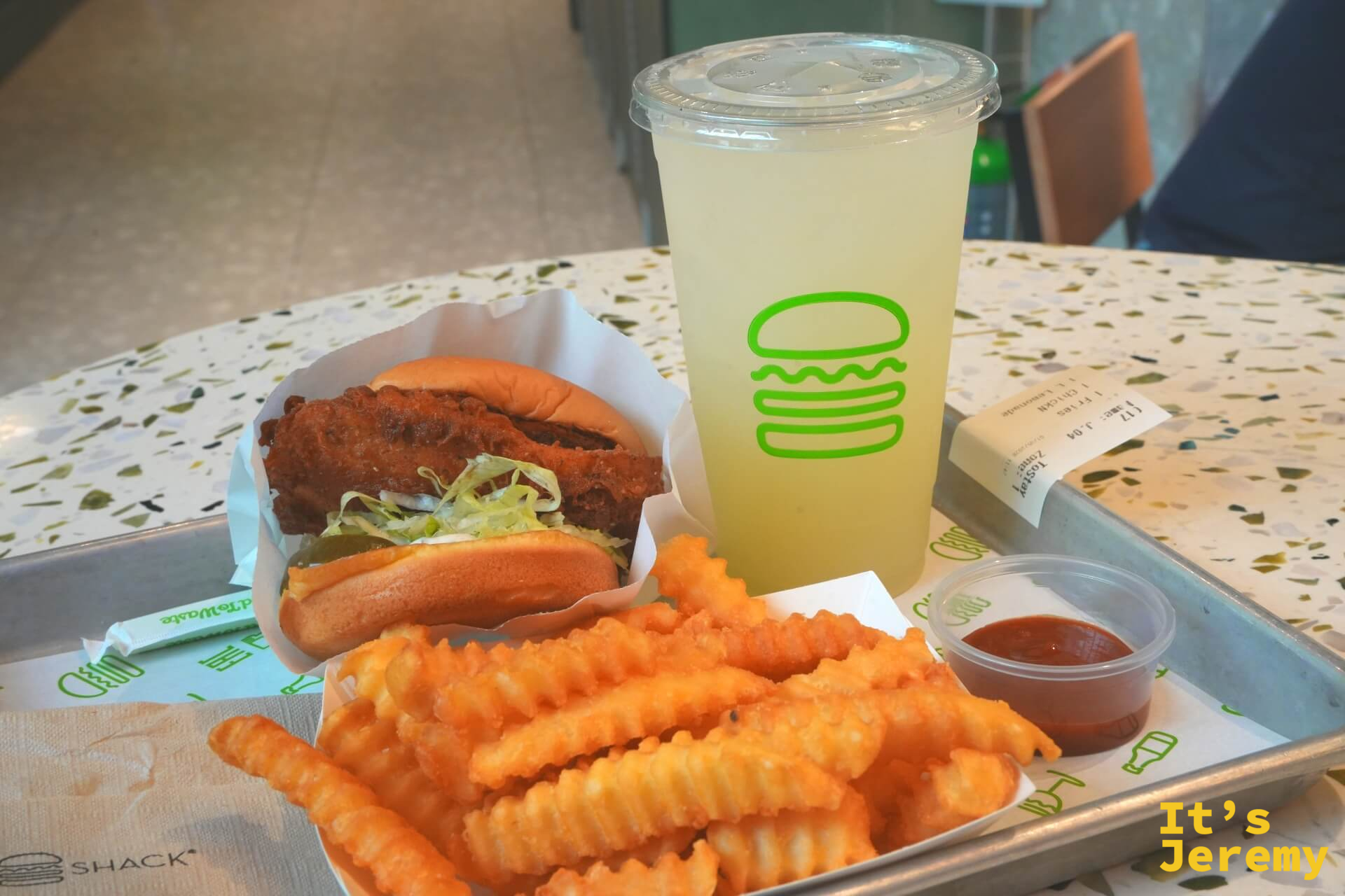 ChickN 雞肉堡、脆薯條、大杯 Lemonade,Shake Shack 標誌托盤,桌上有收據