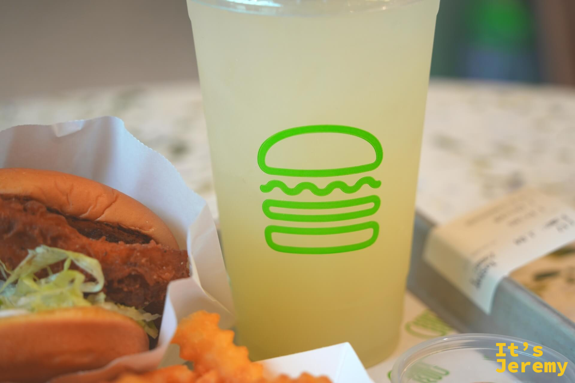 Shake Shack 大杯 Lemonade 特寫,淡黃色清澈飲料裝在印有綠色漢堡 logo 的杯子裡