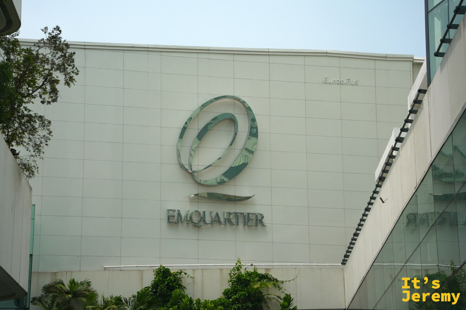 EmQuartier 外觀正面,標誌性的「@」形 logo 在白色外牆上,藍天背景