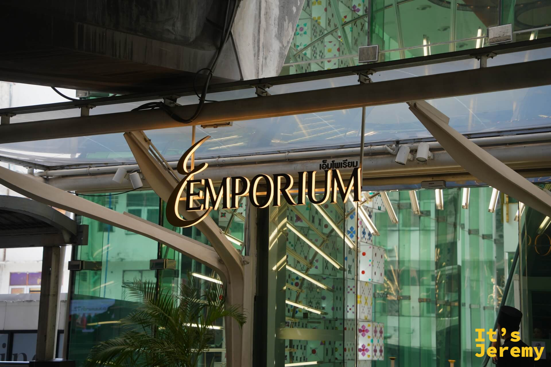 Emporium 入口玻璃頂棚下的金色「EMPORIUM」燙金招牌,有保安站在旁邊