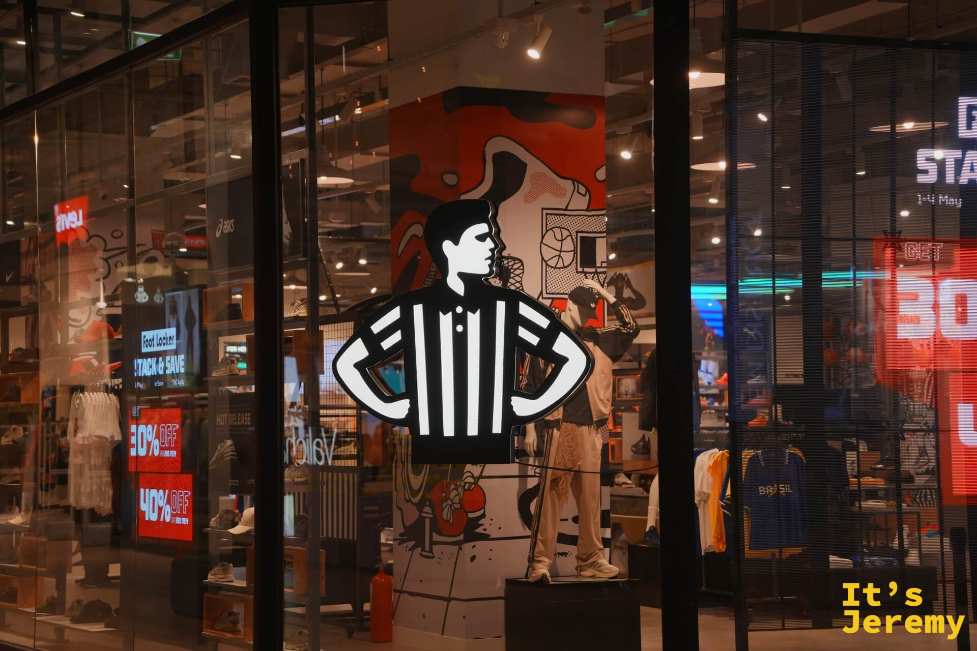 Foot Locker 夜晚櫥窗,霓虹裁判員剪影,背景可見多個運動品牌的鞋款陳設