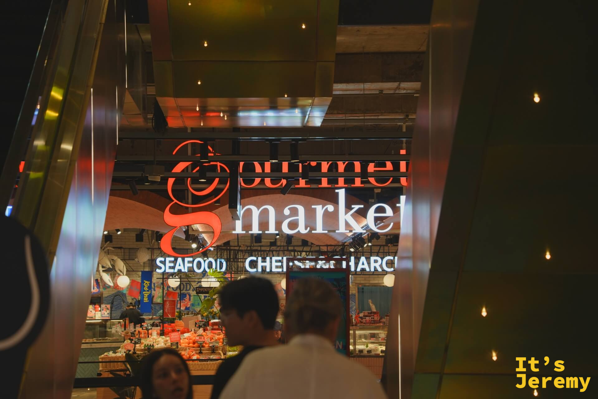 夜晚從外部框景看 Gourmet Market,拱形構圖,店內人來人往