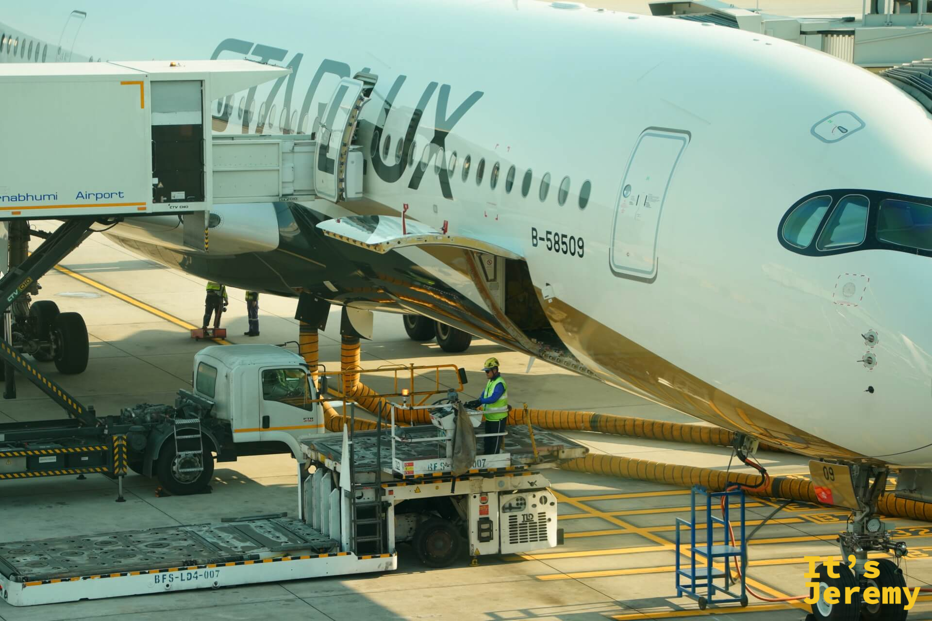 停機坪上地勤人員對星宇航空 STARLUX 飛機機腹進行加油作業,黃色油管連接著機身