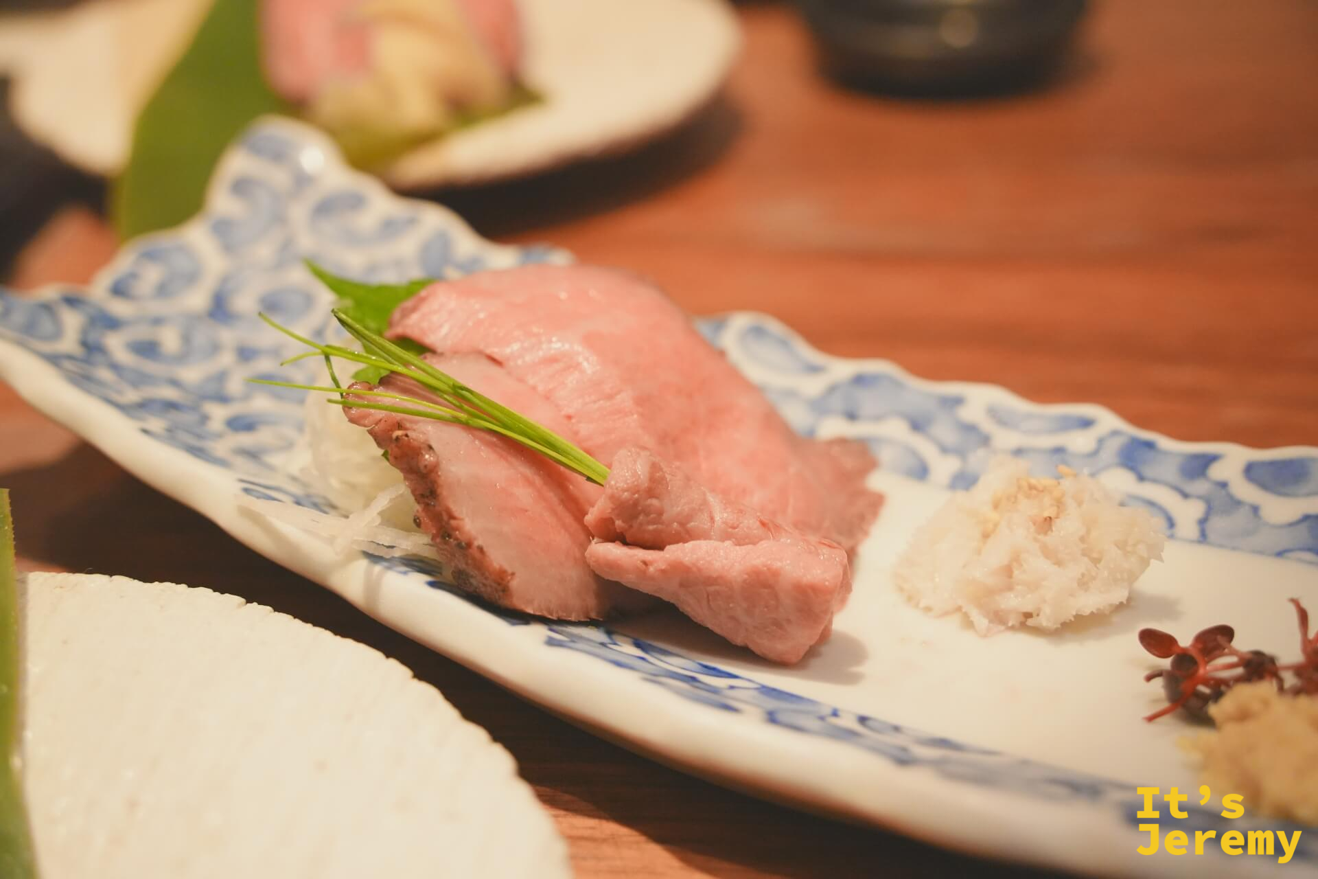 飛騨牛握壽司,藍白花紋陶盤,霜降肉片旁附白蘿蔔泥與芽苗菜