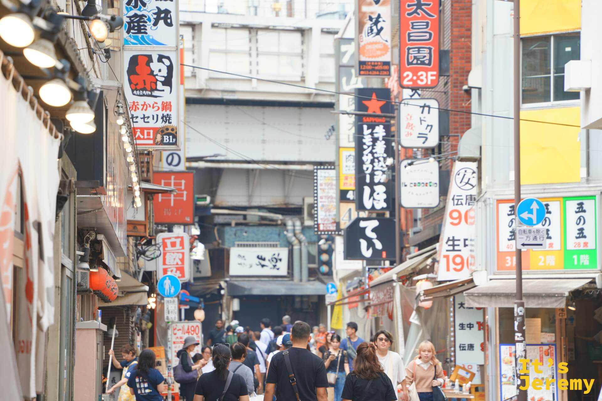 上野アメ横商店街,密集的日式招牌從兩側建築延伸而出,居酒屋、海鮮攤、藥妝招牌擠在一起,人潮緩緩移動